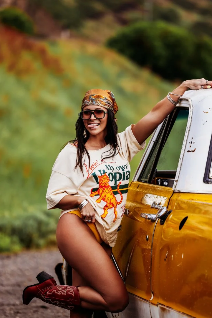 Woman with dark hair wearing a colorful headscarf glasses and a loose T-shirt with 