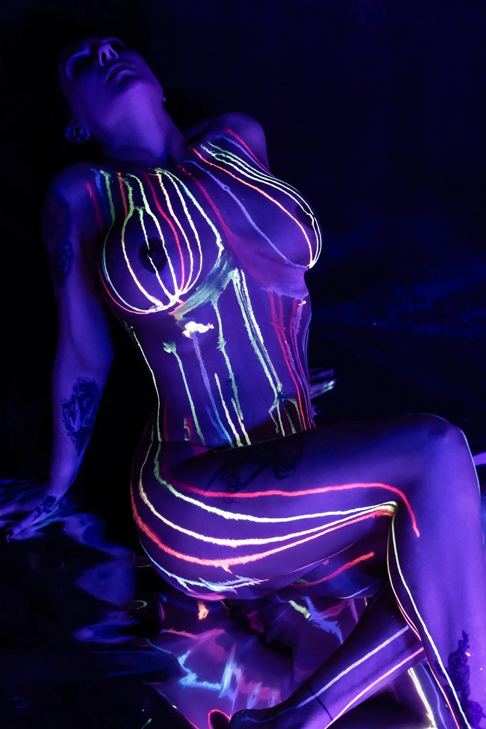 A figure glowing with fluorescent body paint under blacklight
