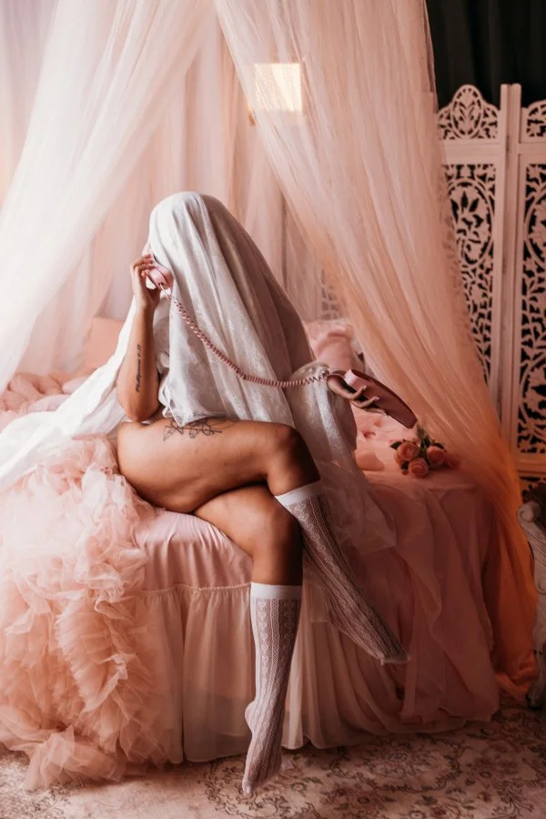 Seated sheet ghost holding a pink telephone under a sheer canopy, Salt Lake City Halloween boudoir