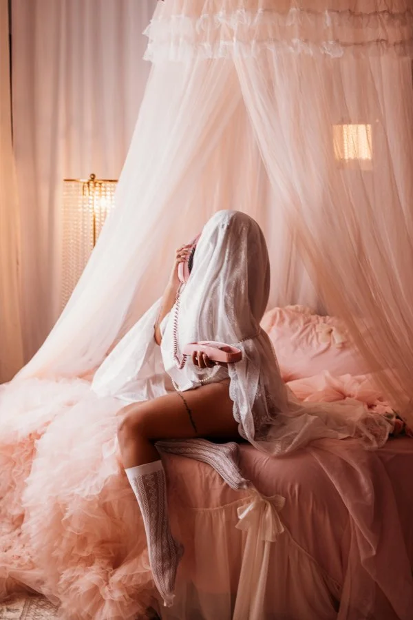 Playful sheet ghost chatting on a pink rotary phone, blush canopy bedroom, Halloween mini session
