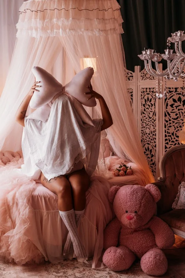Sheet ghost posing with giant pink bow pillow and plush teddy, cute Halloween boudoir Utah