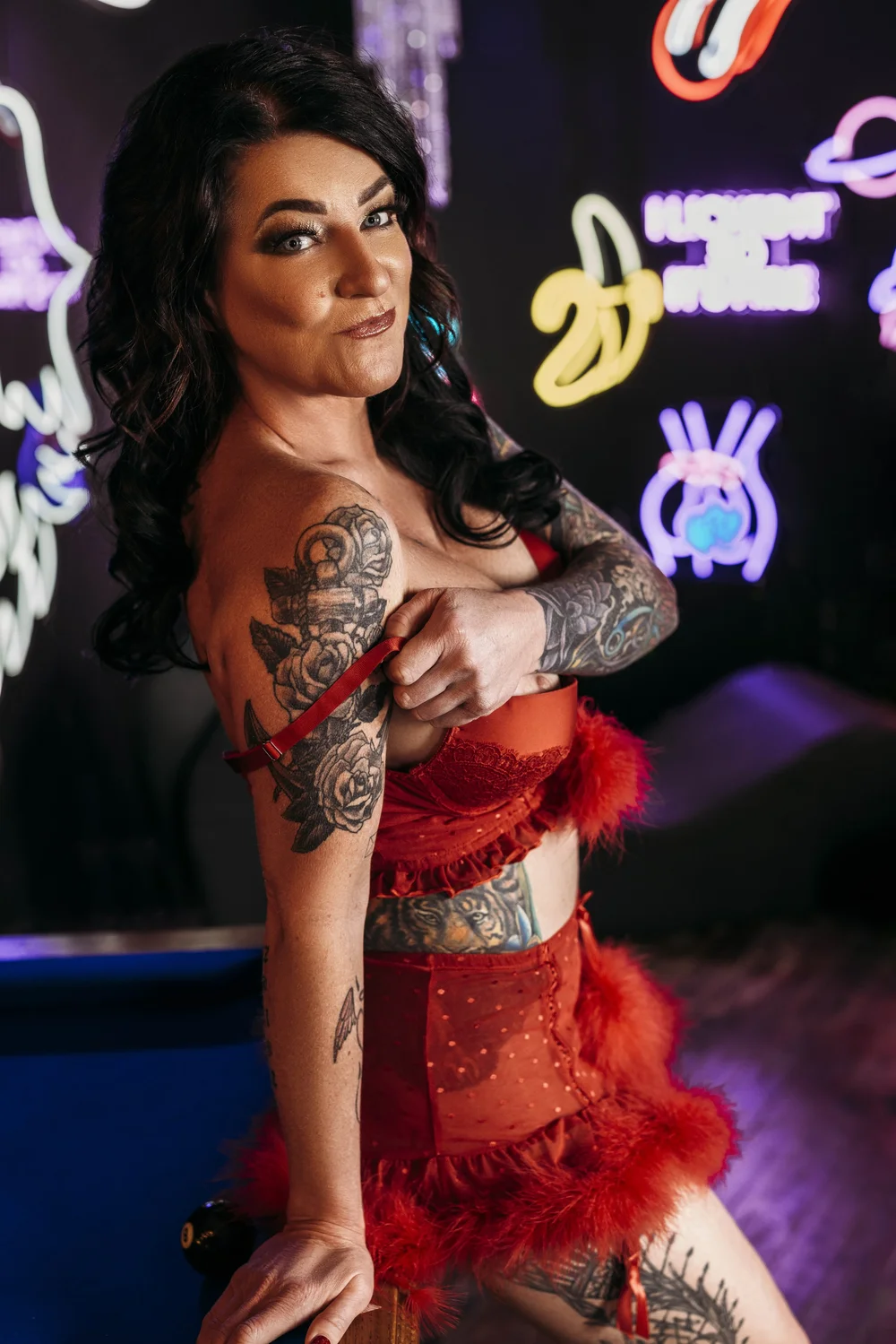 A woman in red lingerie posing in front of neon signs