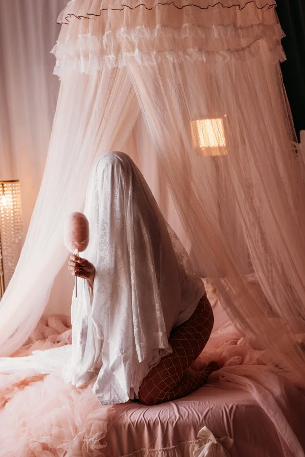 Sheet ghost from behind with cotton candy, pink bedding, fun Halloween boudoir photography