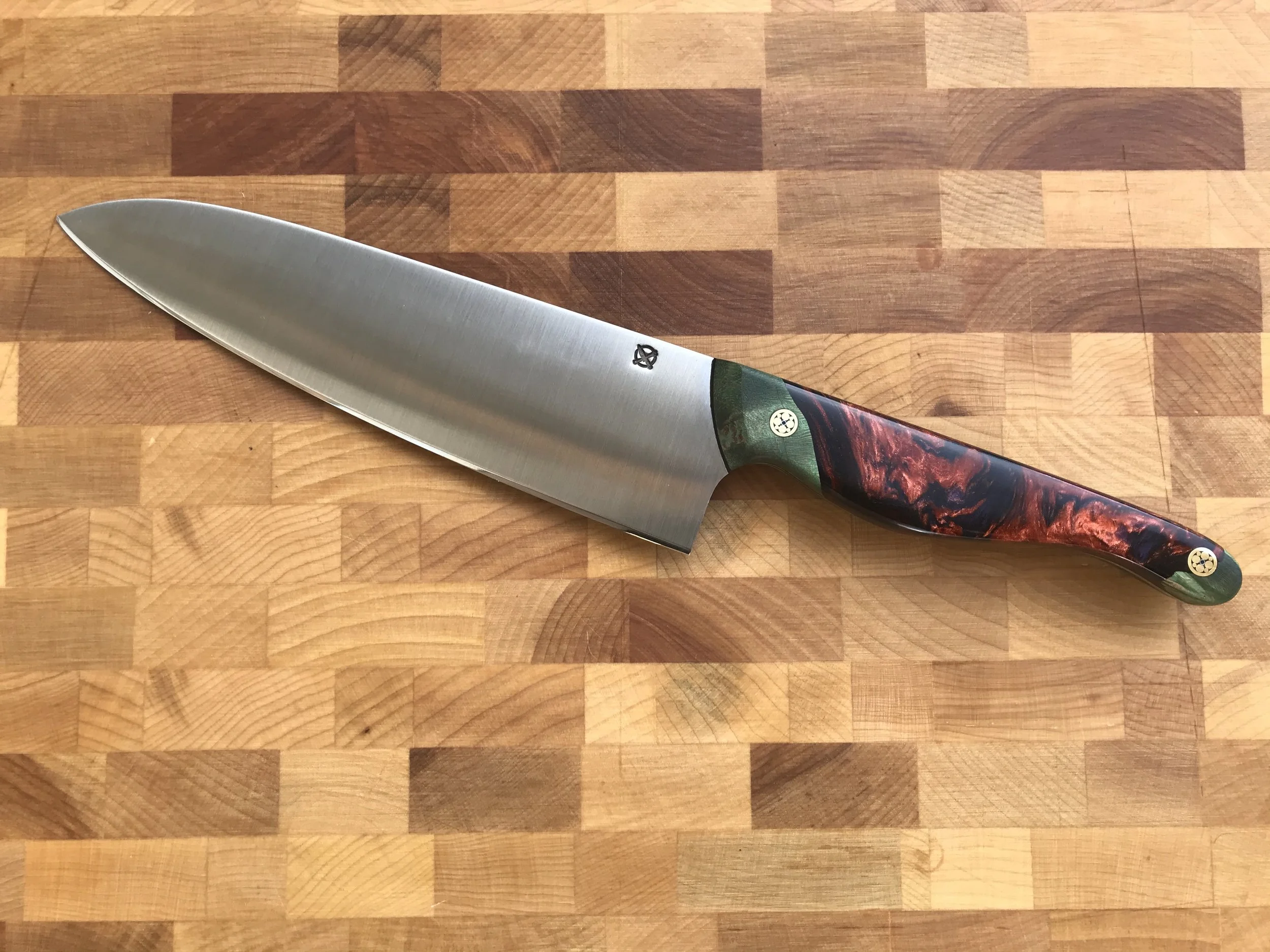 A stainless steel chef's knife with a colorful handle resting on a wooden cutting board.