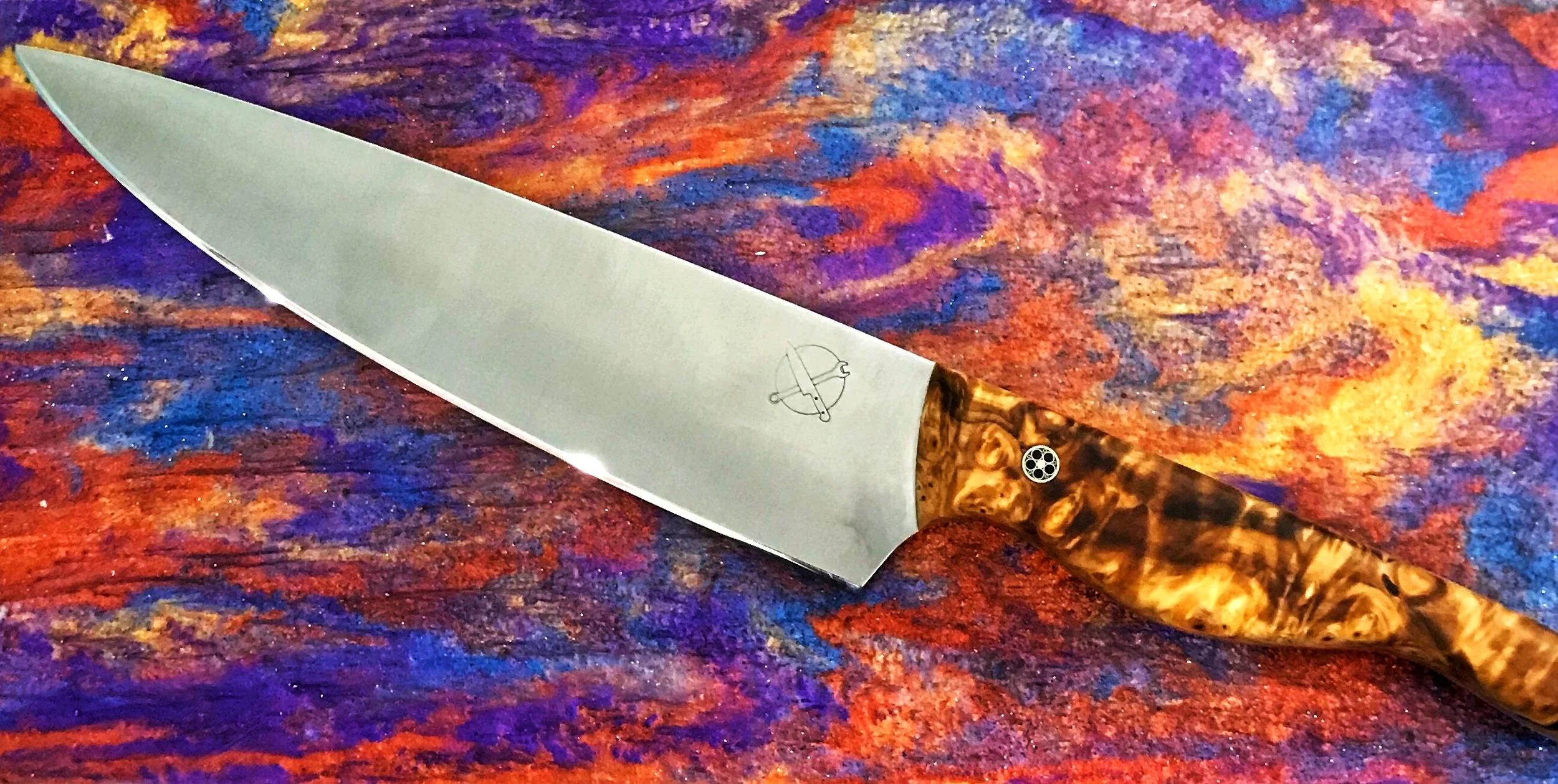 Chef's knife with a patterned wooden handle lying on a colorful, abstract background.