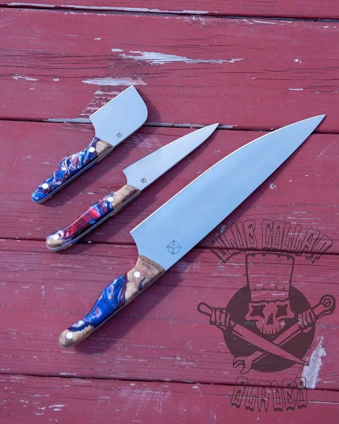 Three knives with colorful, patterned handles laid out on a red wooden surface.