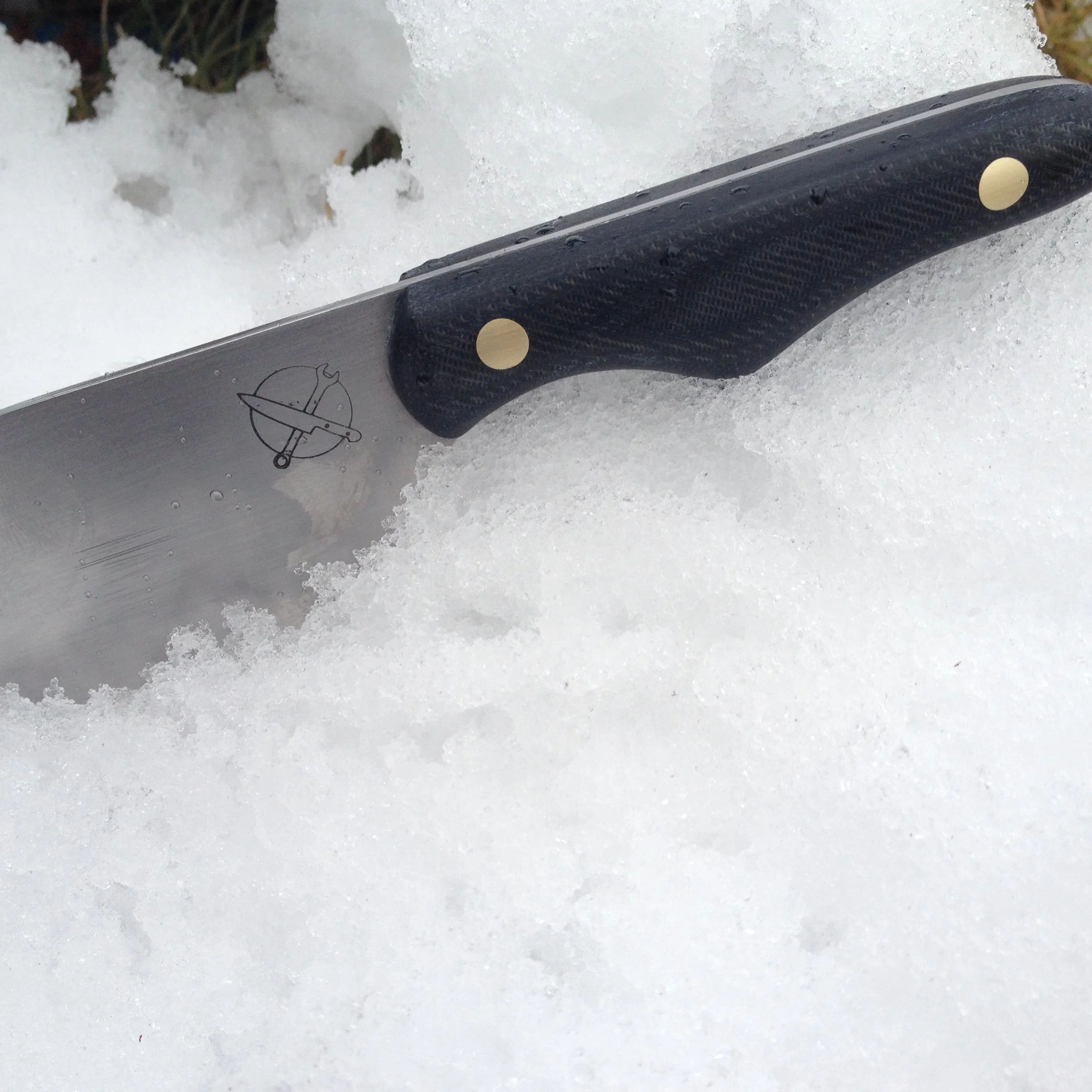 Blue Collar Blades 'prison shank' mini-cleaver knife with reposed denim scales and solid brass pins resting in a mound of fresh snow.