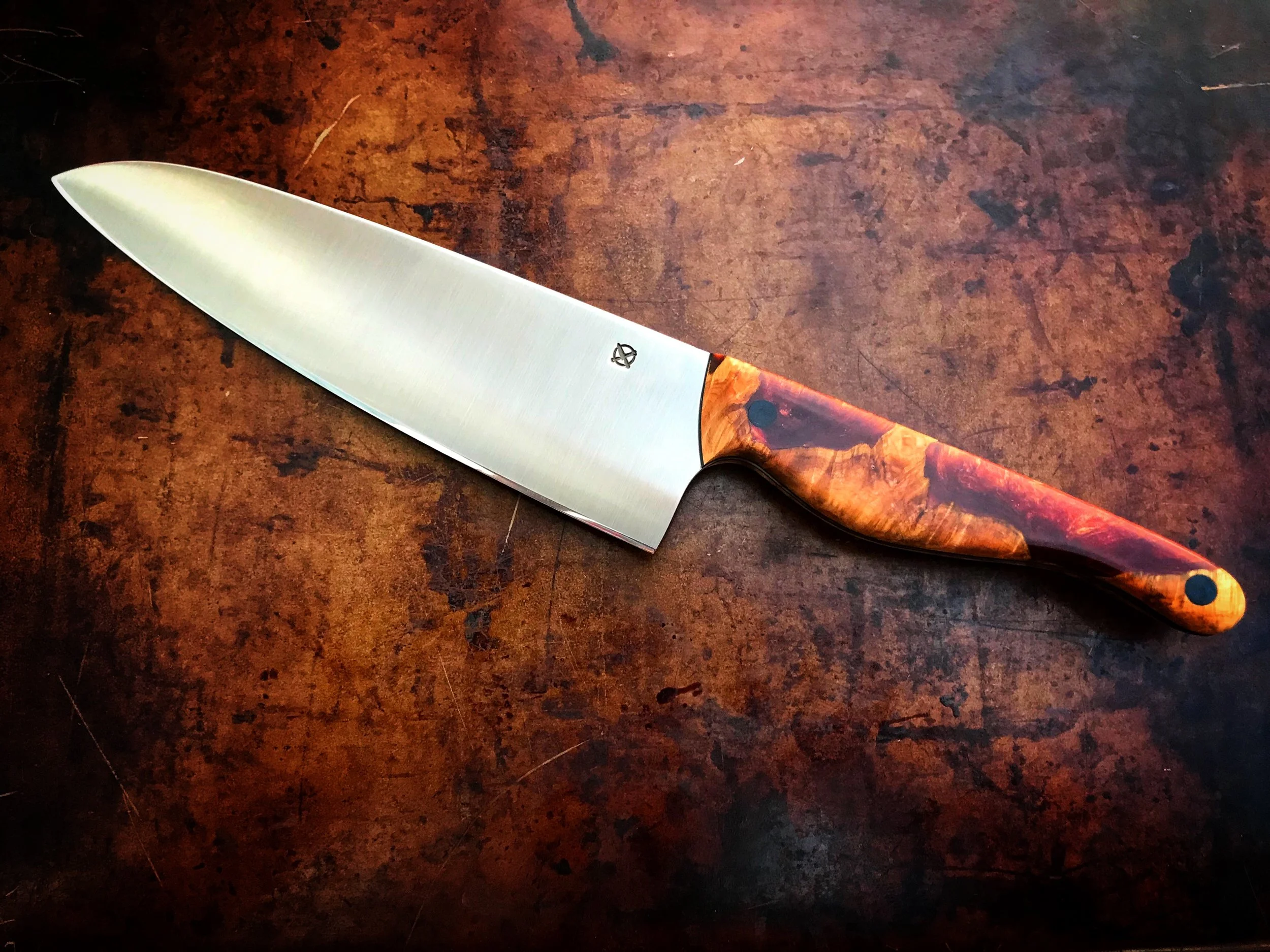 A chef's knife with a wooden handle resting on a wooden surface.
