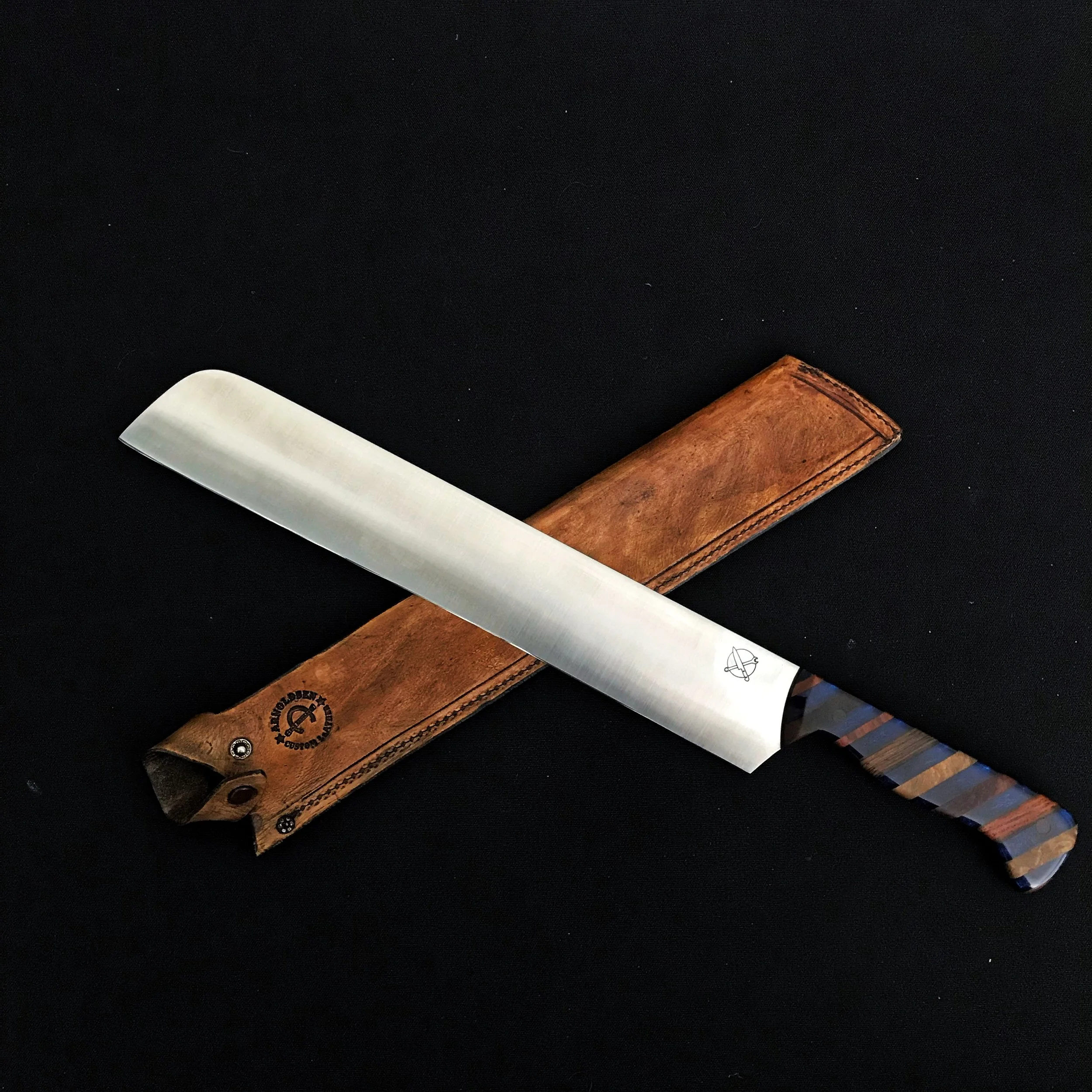 A butcher's knife with a striped blue and brown handle resting on a brown leather sheath against a black background.