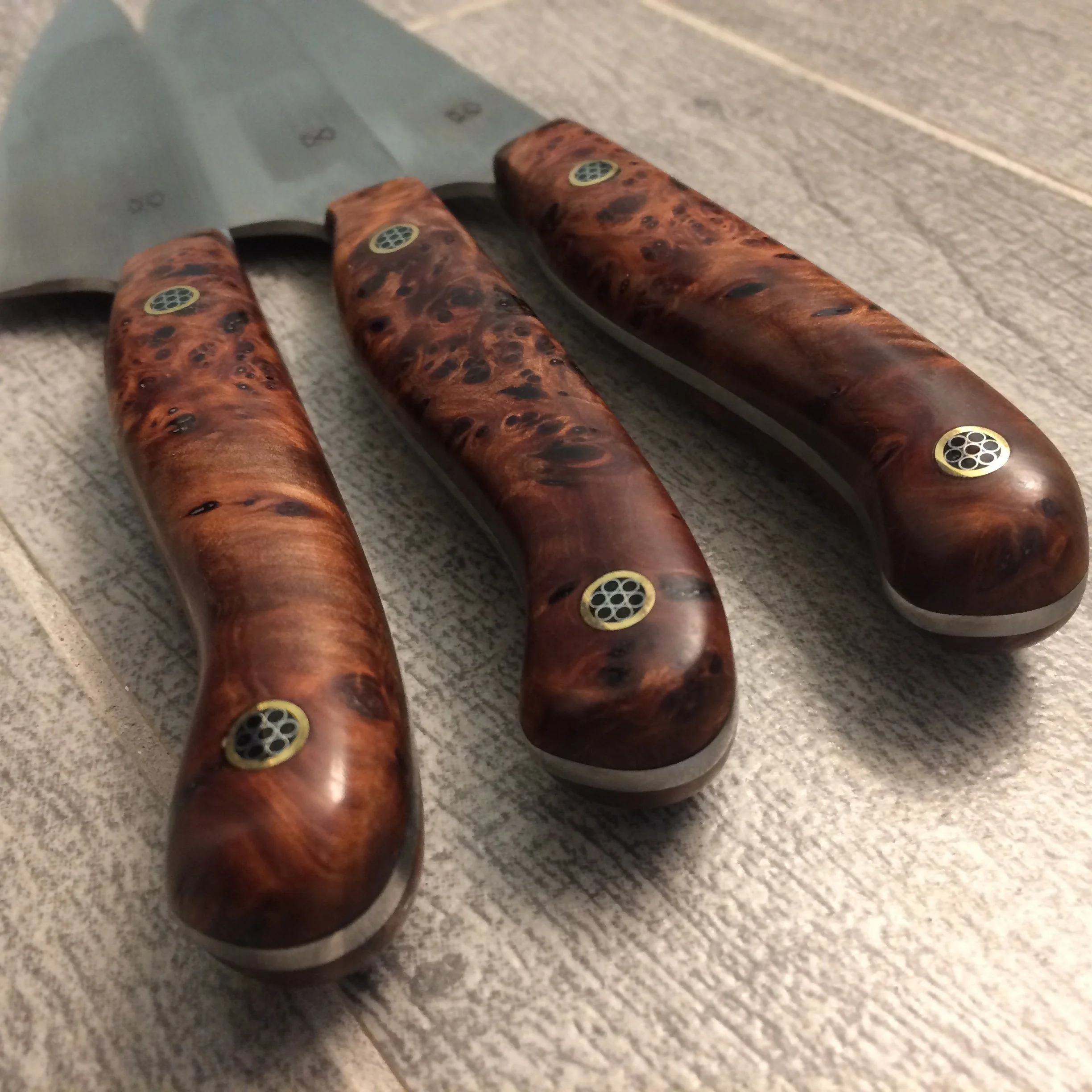 Close-up of a kitchen knife with a wood handle on a textured wooden surface.