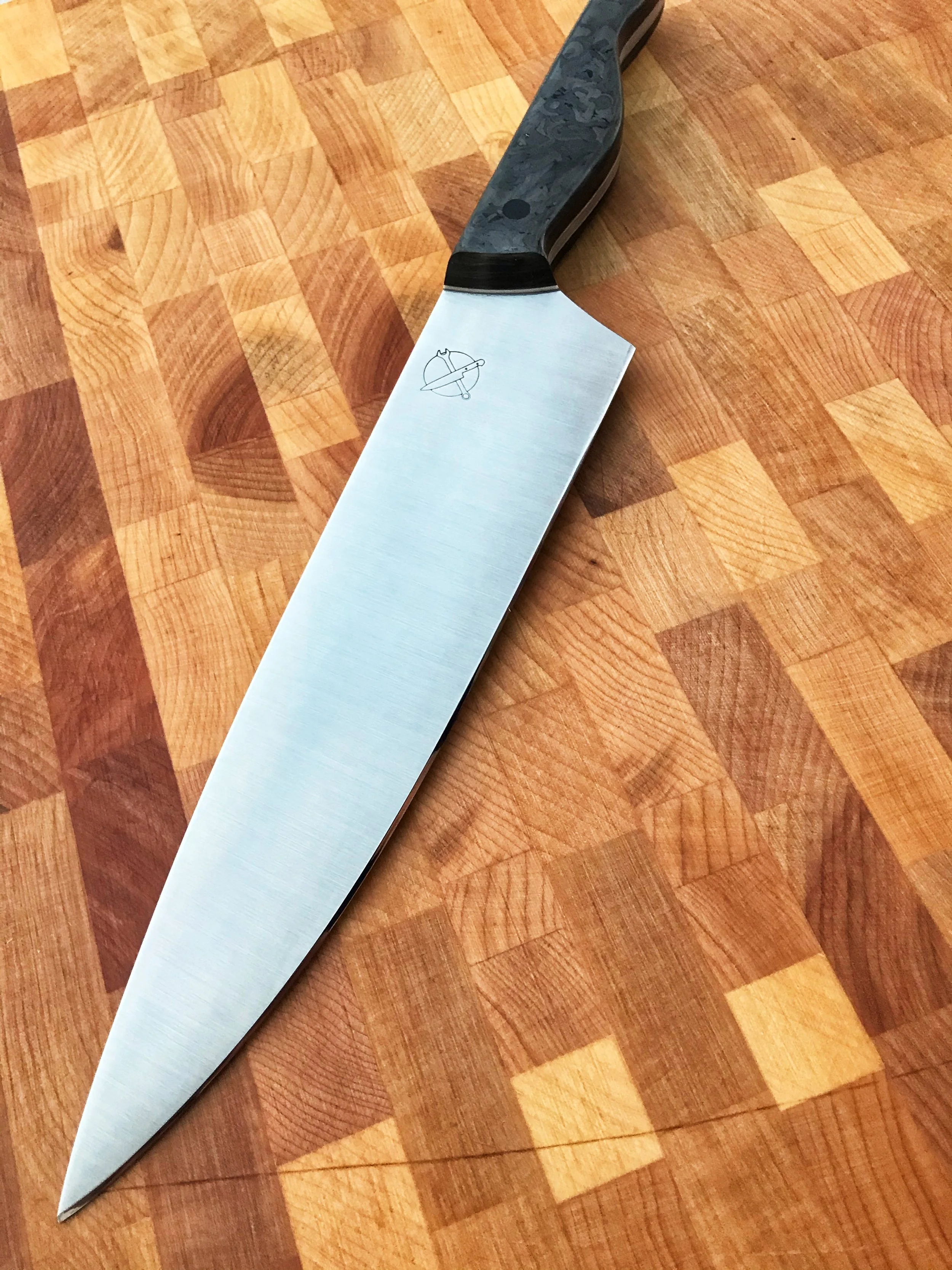 Kitchen knife with a dark handle on a wooden cutting board.