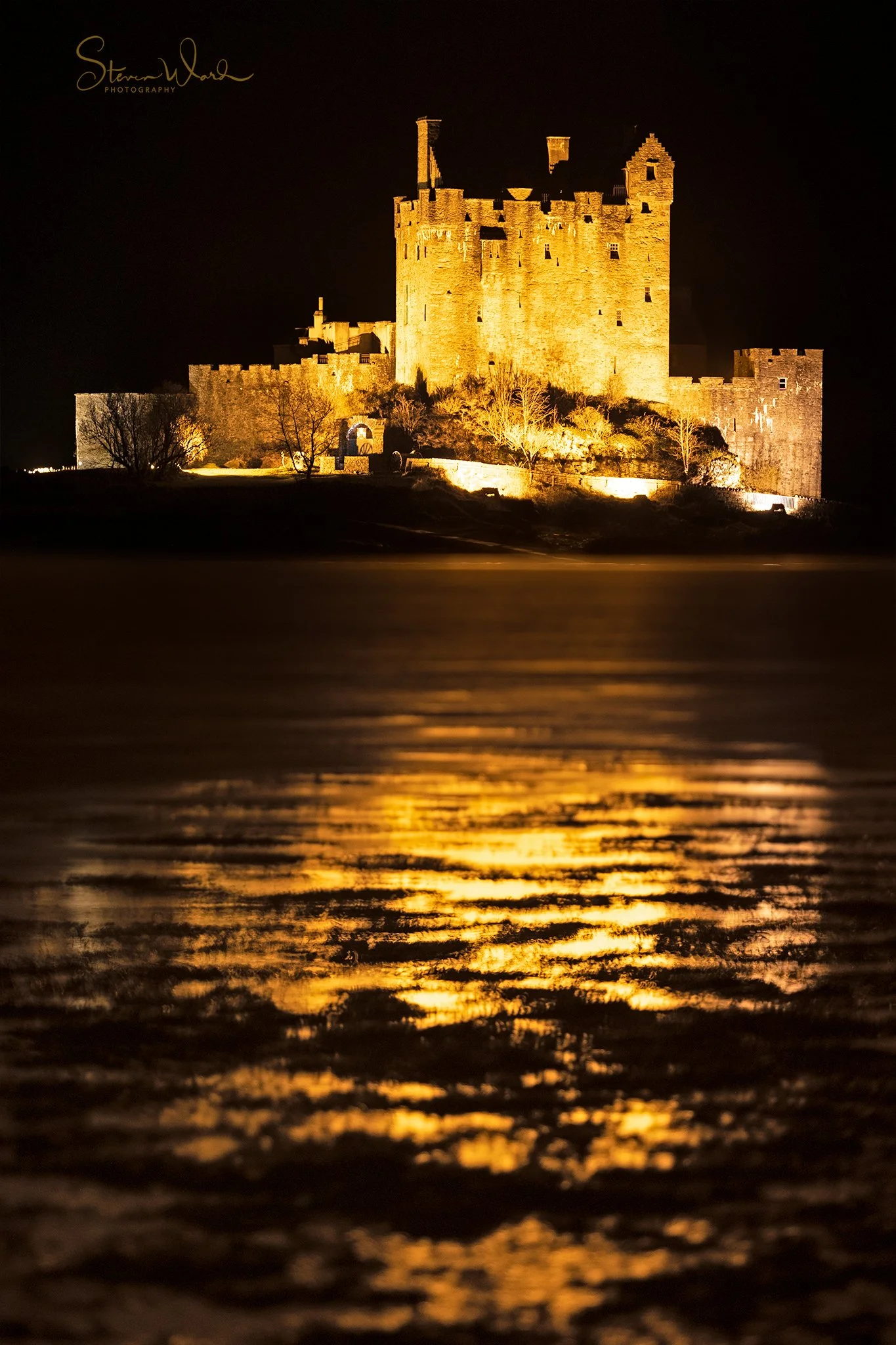 Illuminated castle at night reflected on water