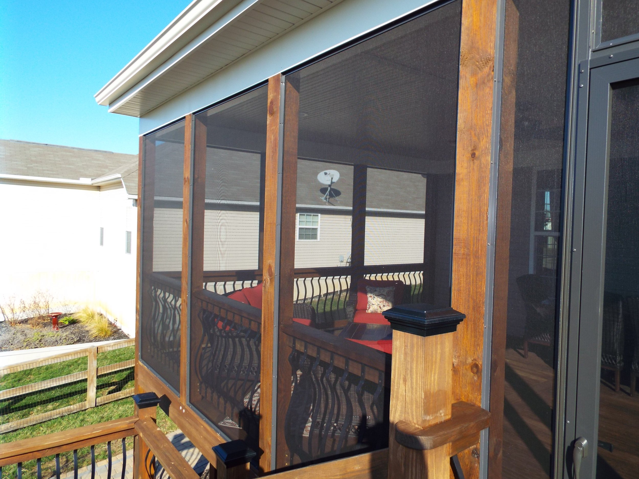 Exterior view of screened in porch. Wooden frame. Neighbor's house in the background.. Furniture seen through the screened windows.