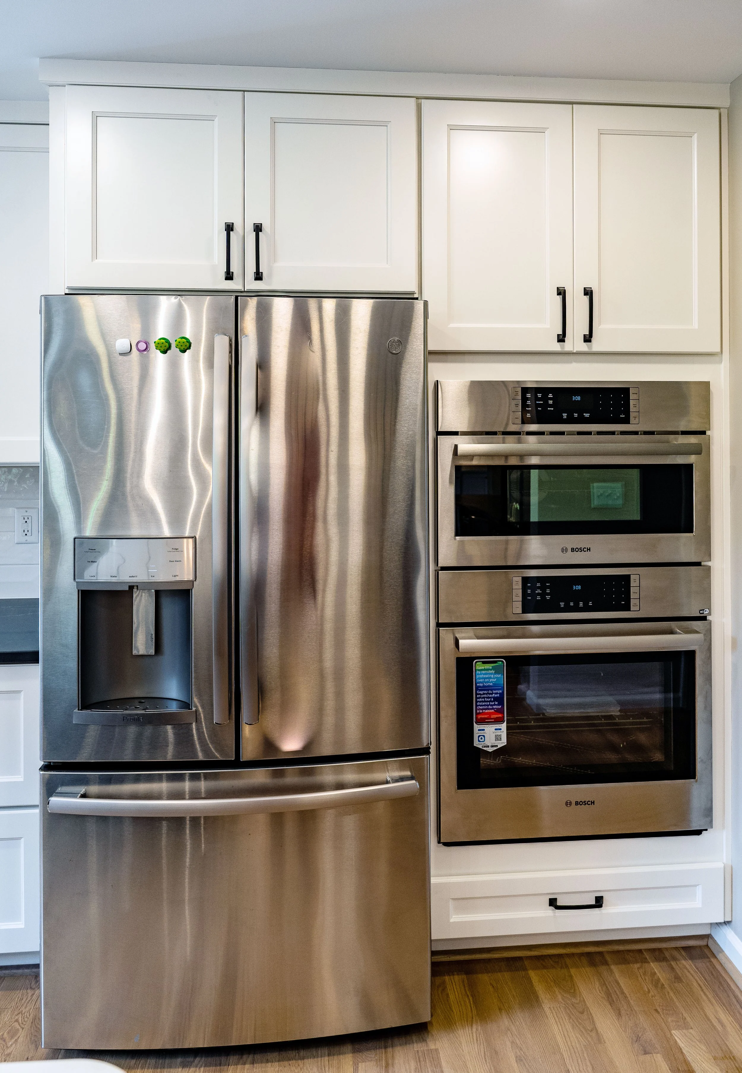 KBC Construction - Whole House Makeover. Open concept kitchen. Stainless steel refrigerator, microwave, and oven. White cabinets. Light plank flooring throughout.