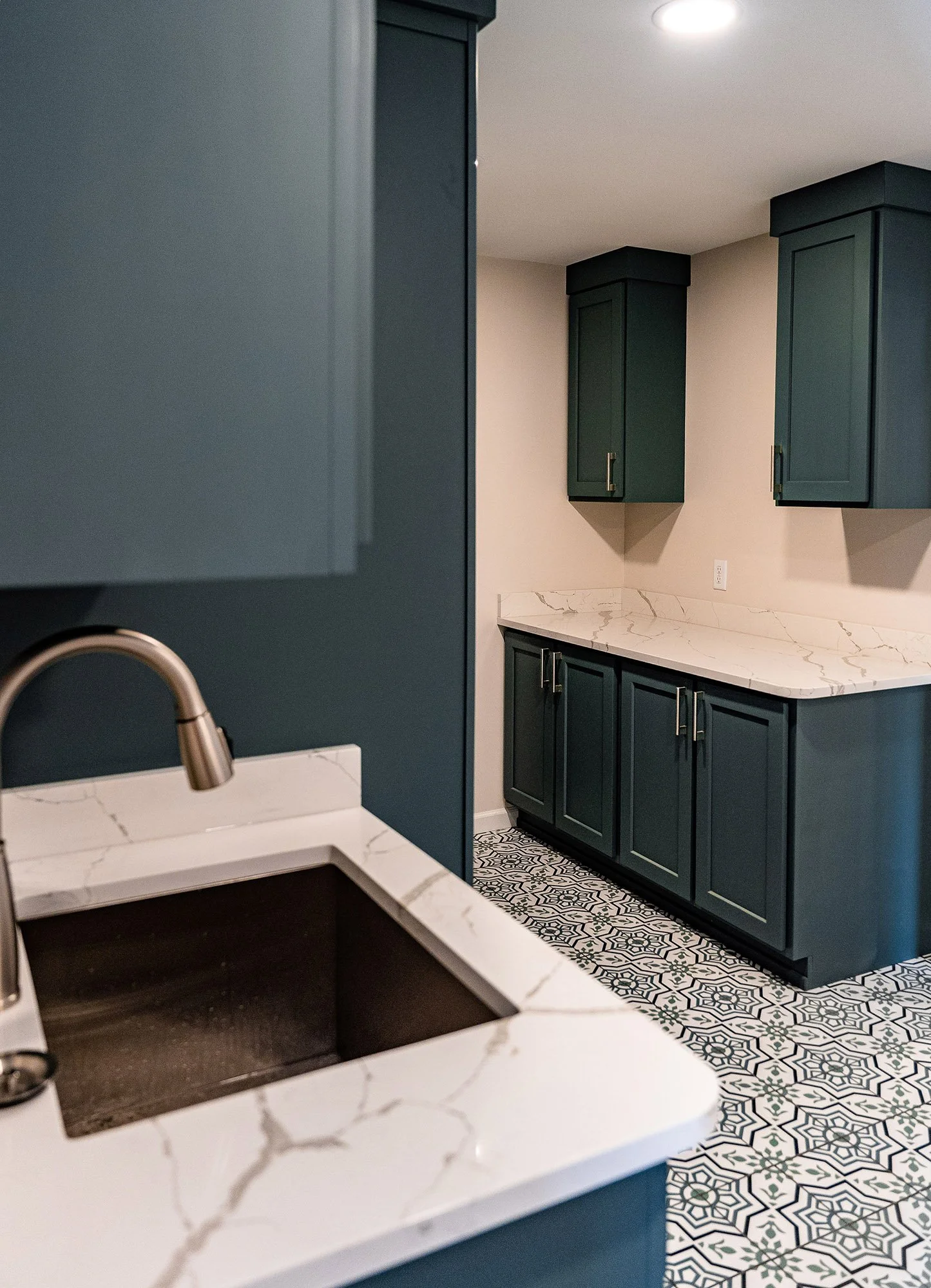 Complete First Floor Remodel by KBC Inc. 
Laundry Room counter and cabinets. Marble counter top with under-mounted sink on left side of photo.  LED lighting. Mosaic pattern tile floor.