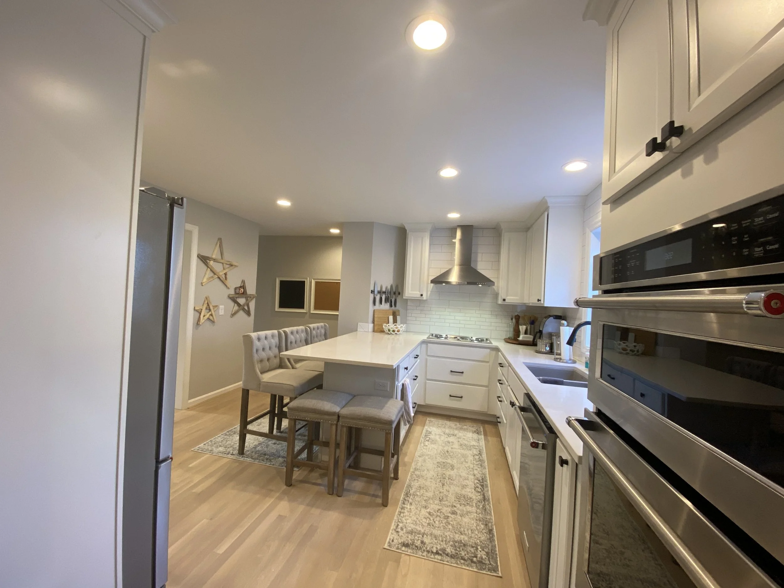 Kitchen counters and appliances. Range hood and stove top between kitchen island and kitchen counters with undermount sink.
Hardwood plank floors and rugs. 