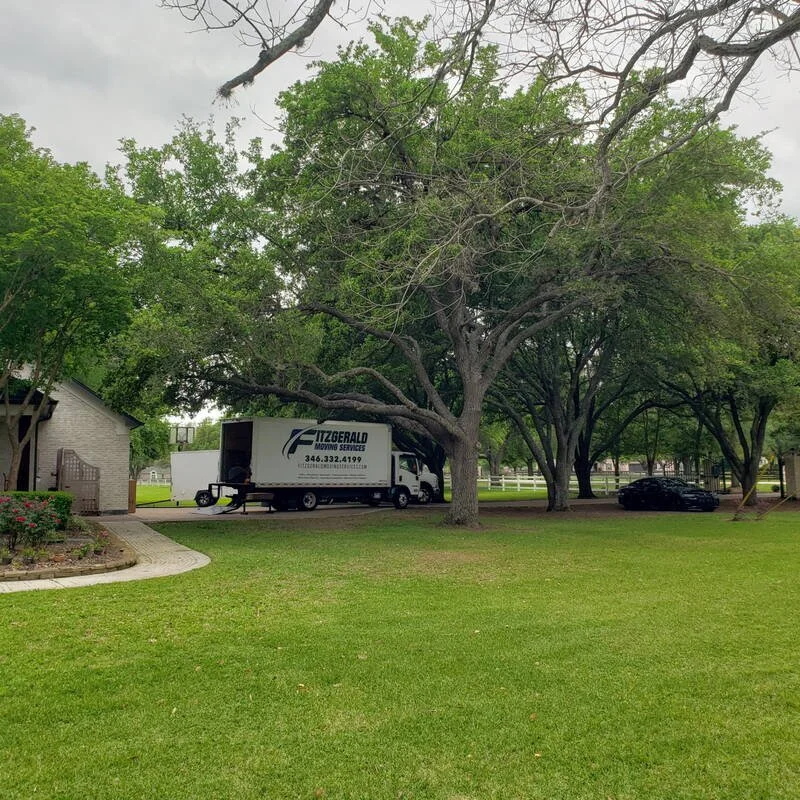 Fitzgerald Moving Services truck at an oak-shaded Houston property