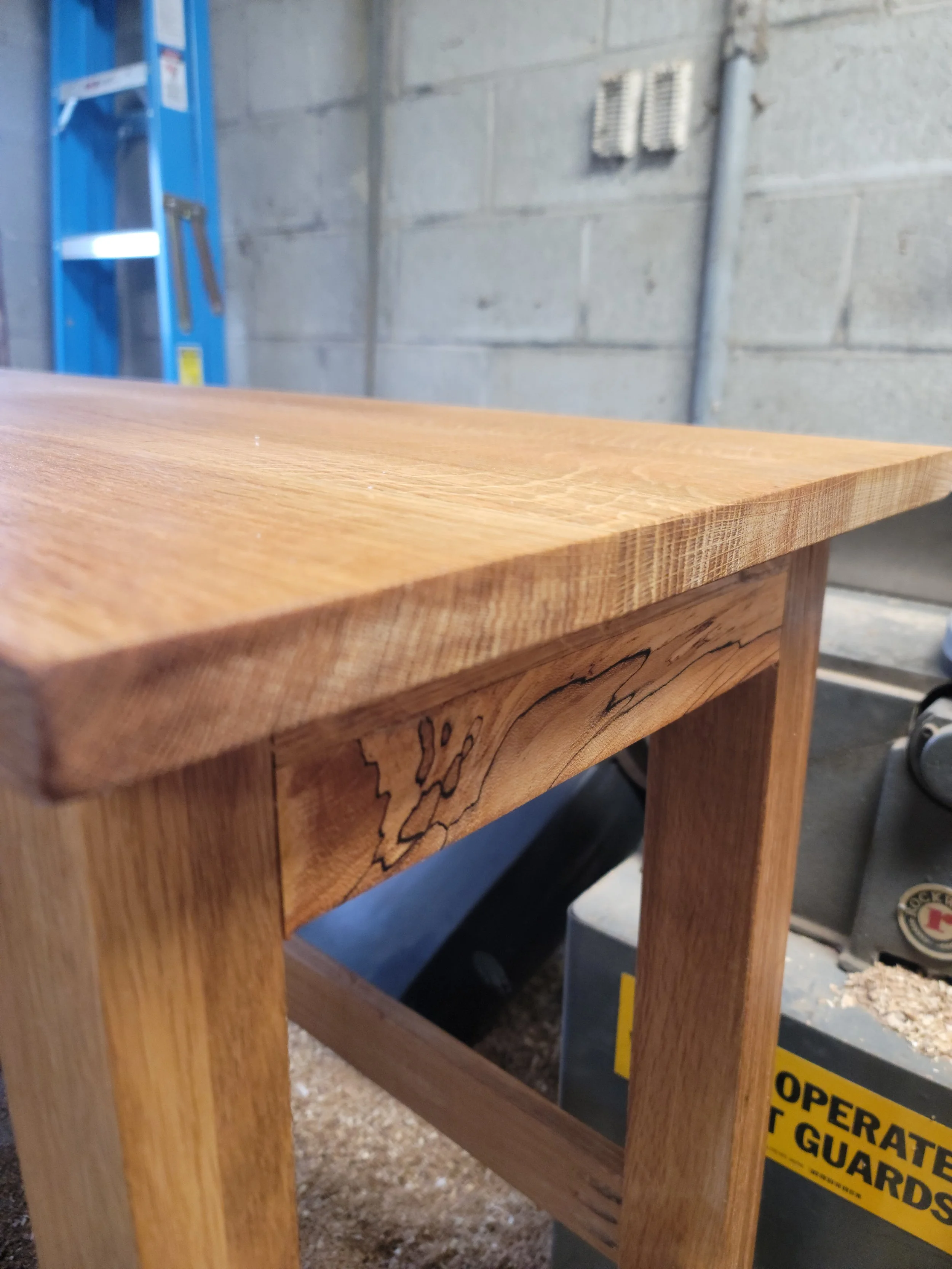 Close-up of a wooden table with a smooth, polished surface and decorative grain in a workshop setting.