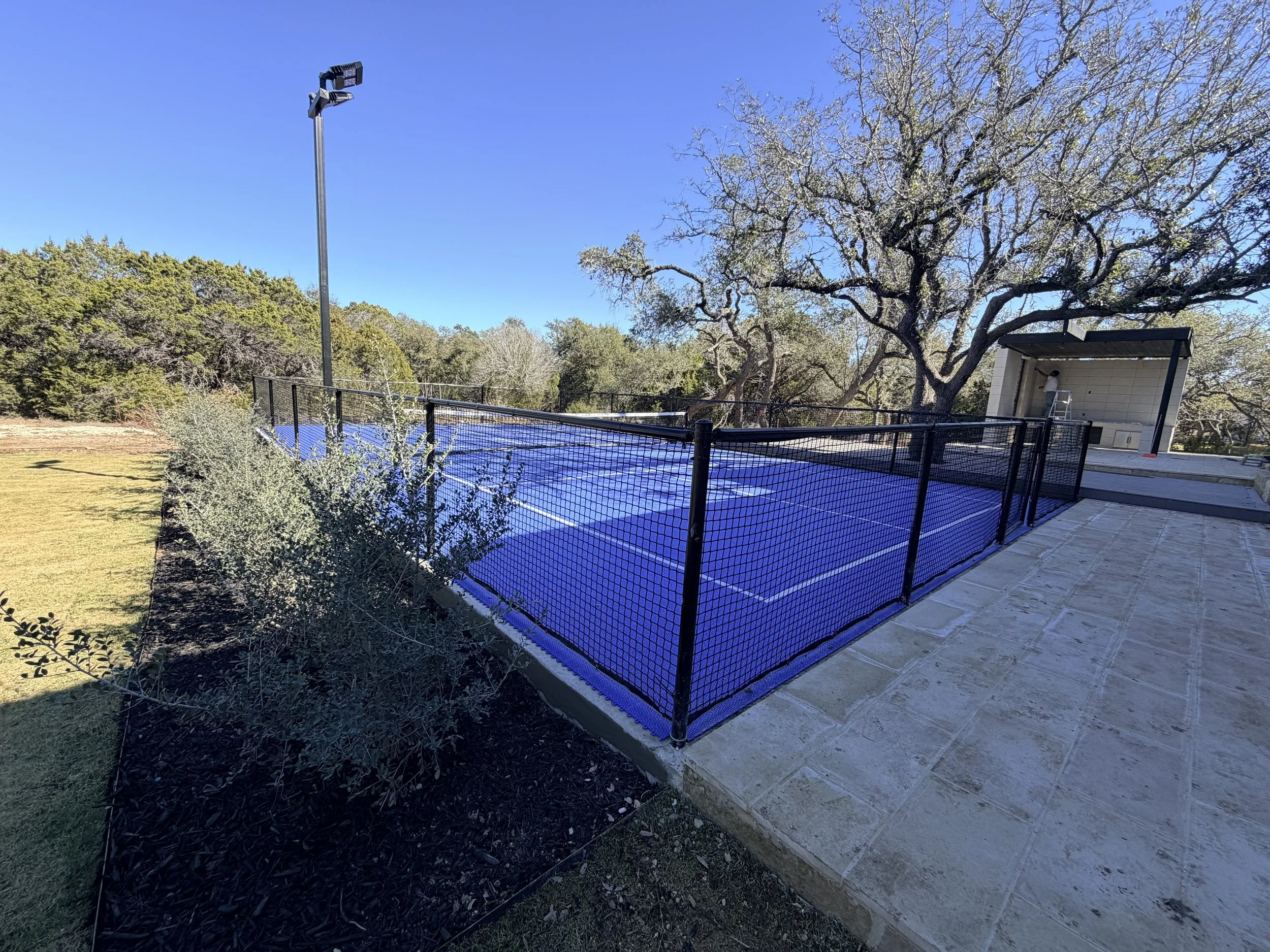 Completed residential pickleball court with acrylic sports surface, fencing, and LED lighting in Boerne, TX