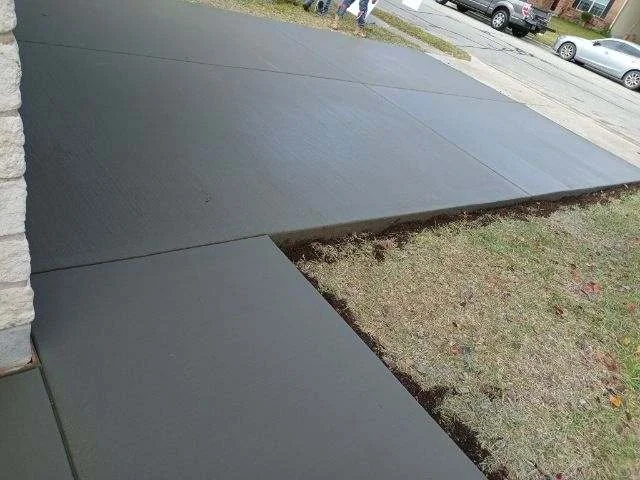 Newly poured concrete sidewalk next to grass with a small section unfinished.