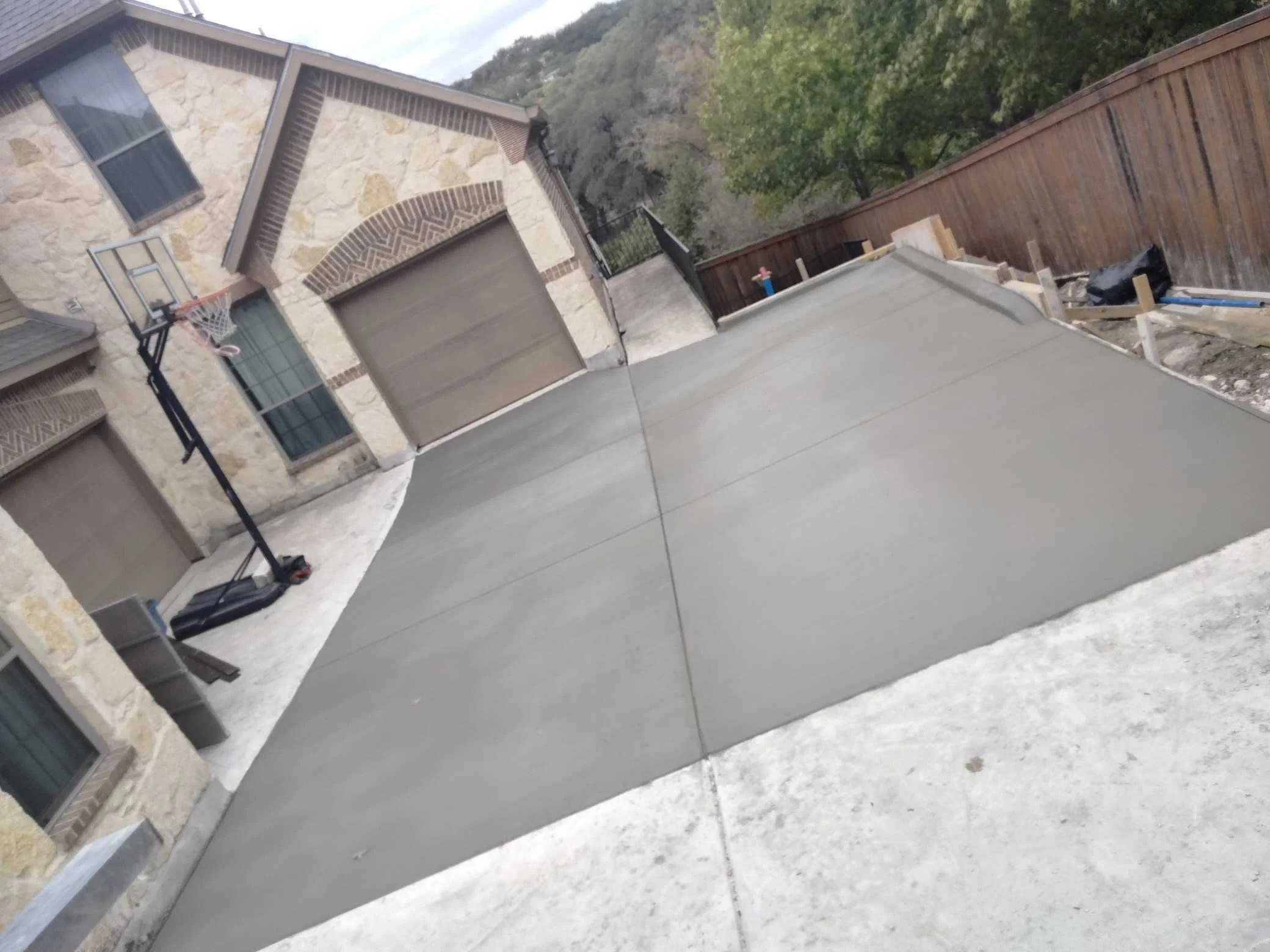 Newly poured concrete driveway in front of a house under construction.
