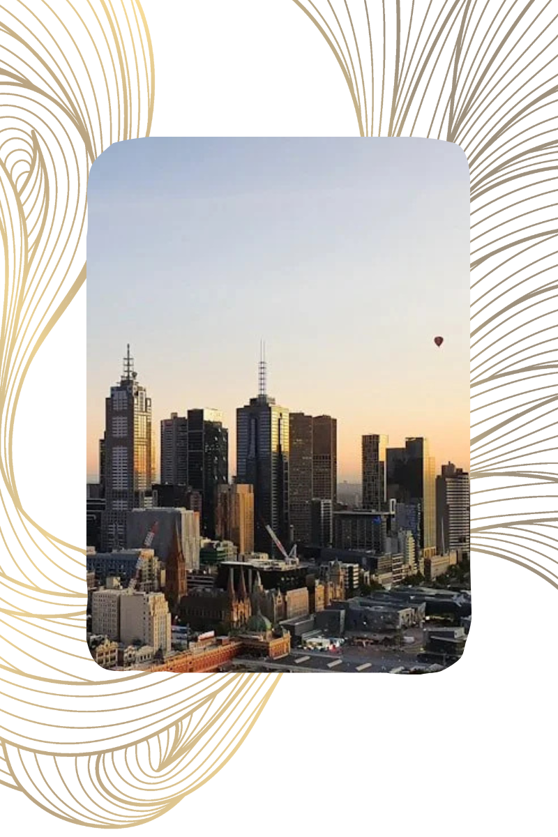 A city skyline at sunset with tall buildings and a hot air balloon in the sky.