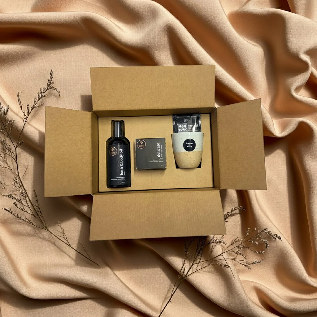 open box with queen of the day items including bath abd body oil pink clay mask and keep cup with tea tonic complextion tea bag