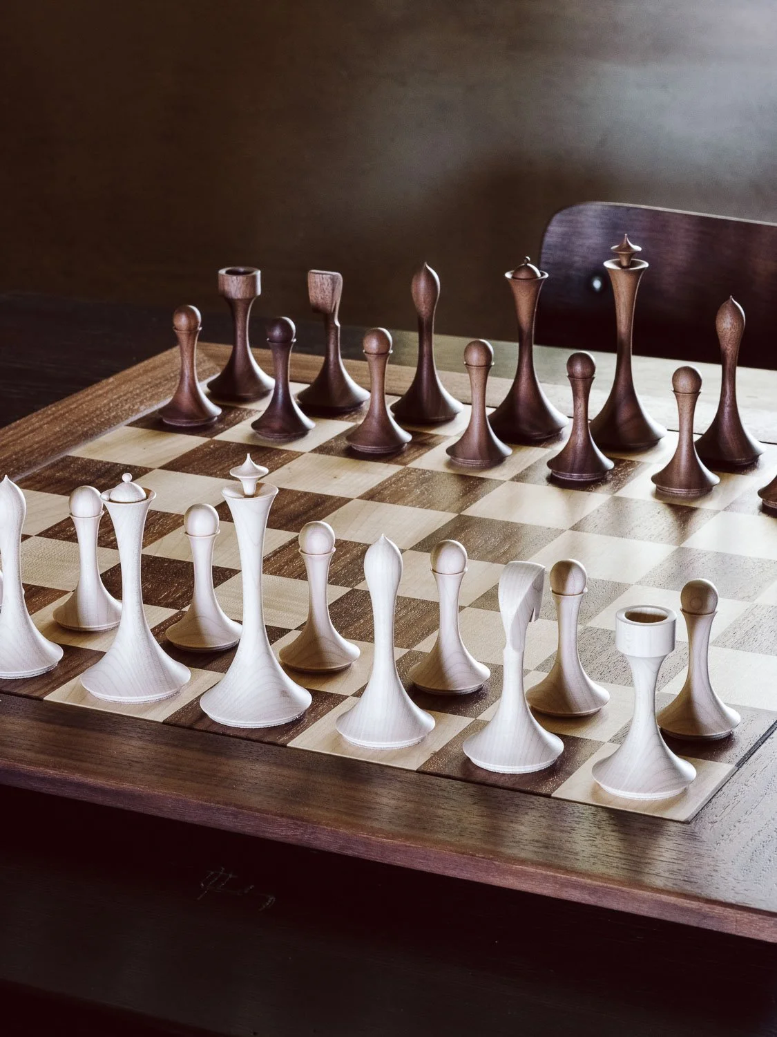 A chessboard with wooden chess pieces in light and dark wood colors.