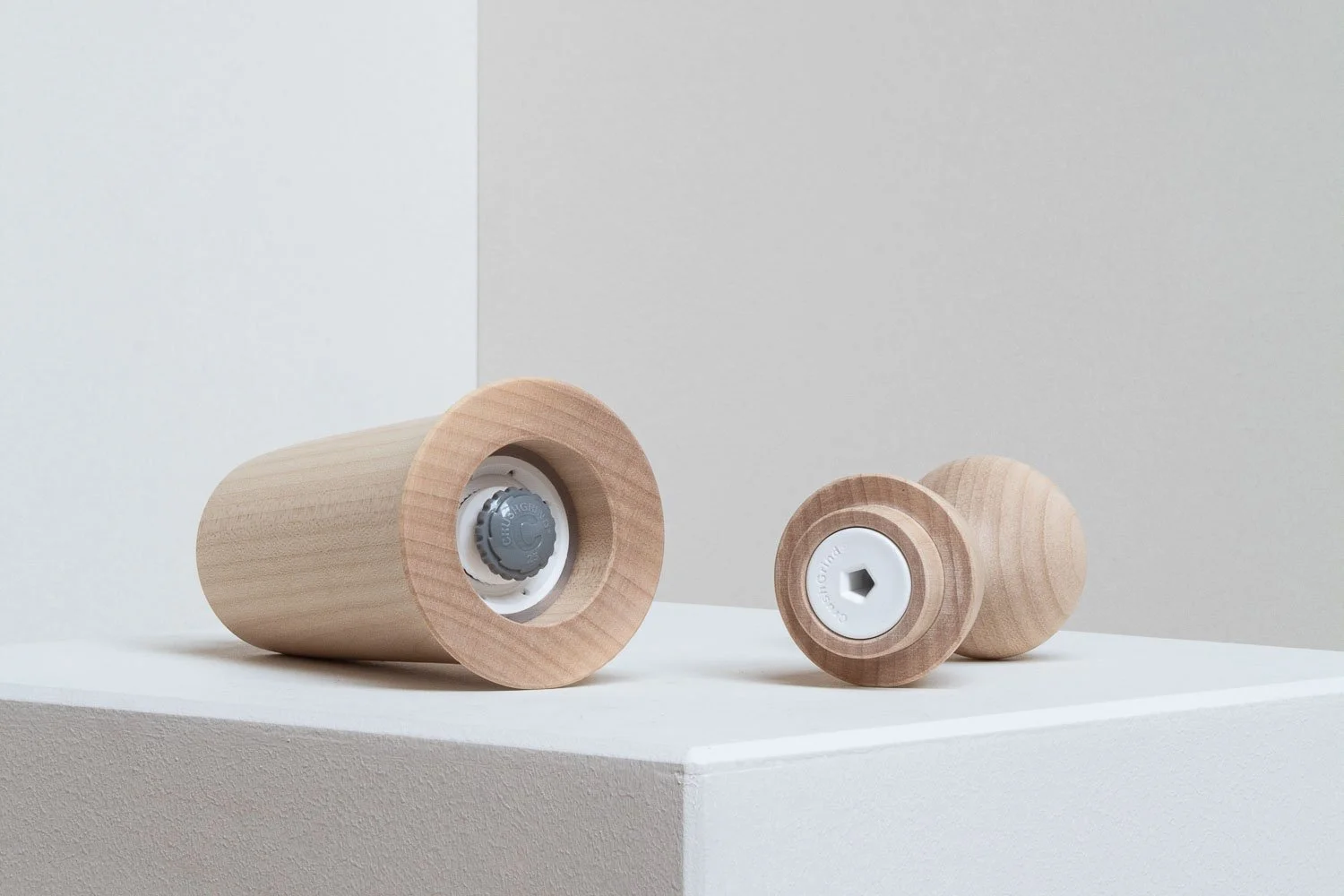 Three wooden objects resembling stamps or tokens with different shaped inserts on a white surface against a light-colored background.