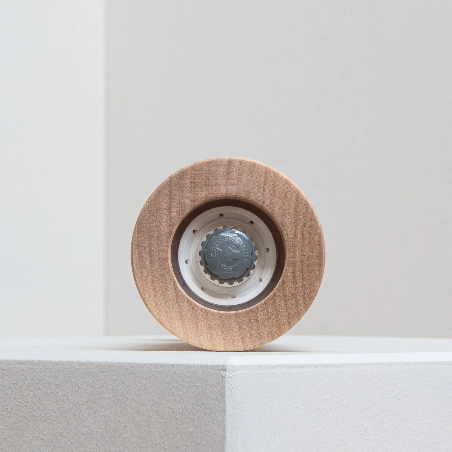 Close-up of a skateboard wheel with a wooden outer layer and a plastic inner core, placed on a white surface against a white background.