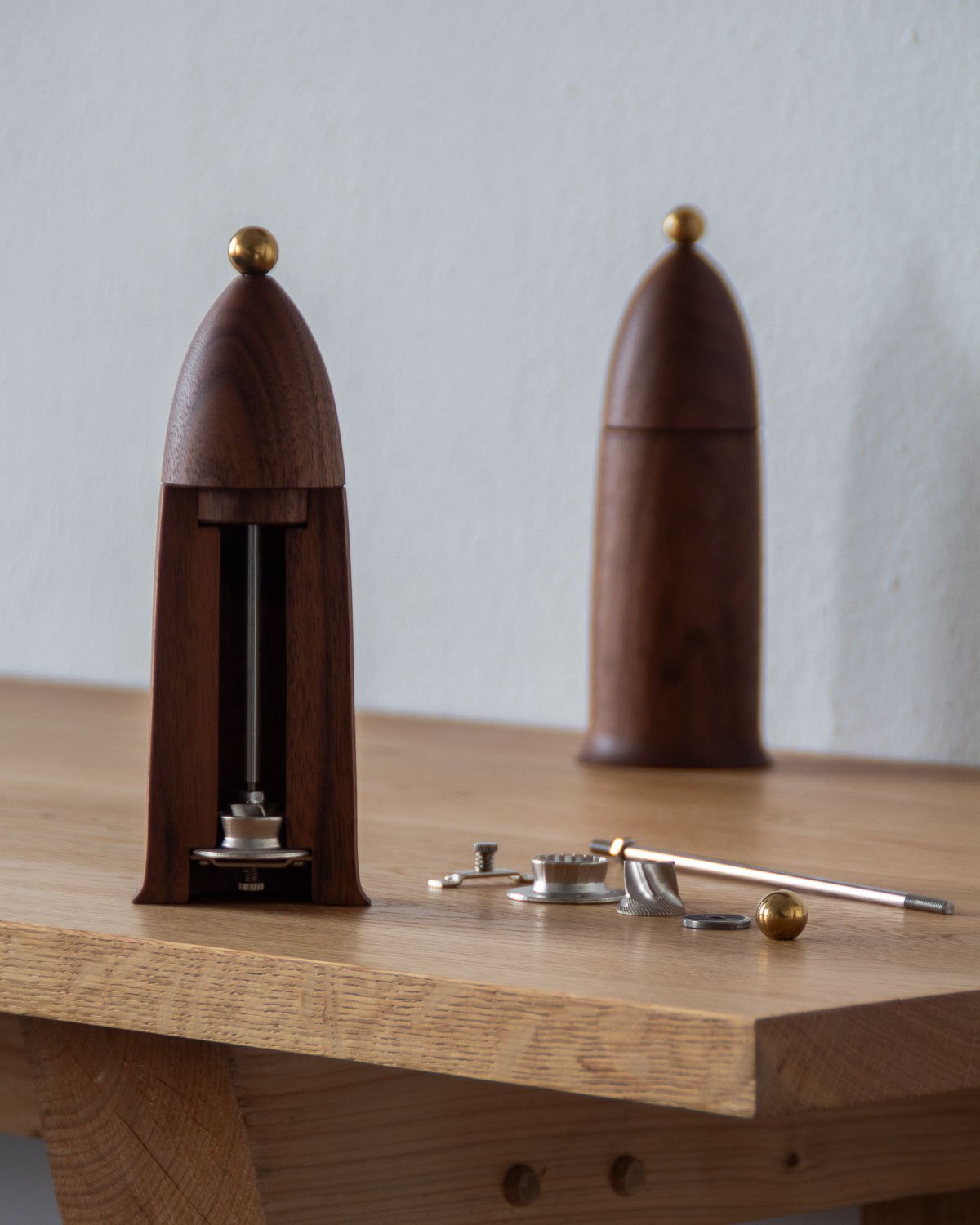 Two wooden sculpture pieces with golden accents, and small metallic tools and objects on a wooden surface.