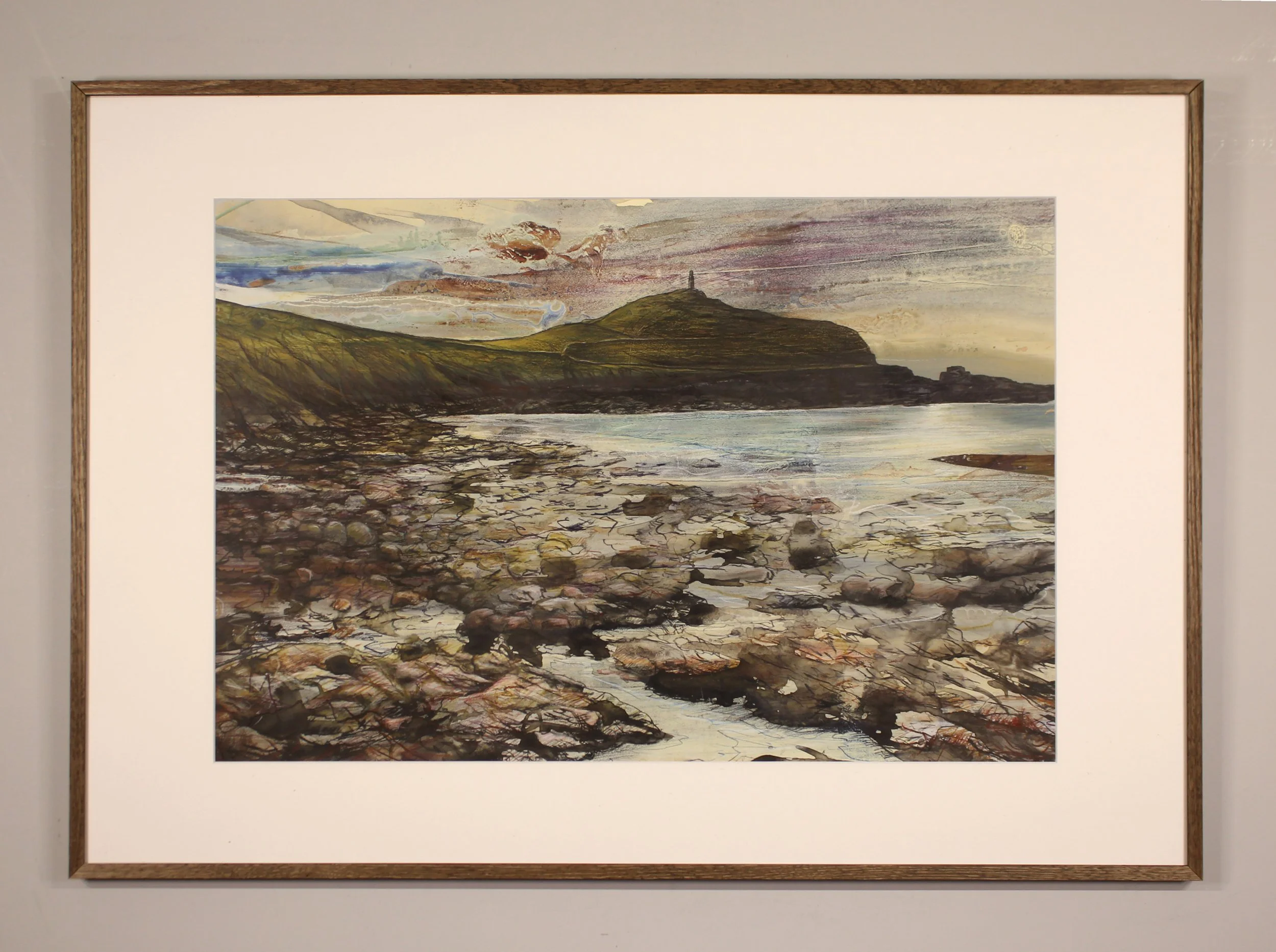 A colourful and moody drawing of a rocky beach with the Cape Cornwall headland on the horizon and a golden soft sunset behind. Expressive mark making ion the fore=ground ctreates the textures of the rocks on the sea shore.