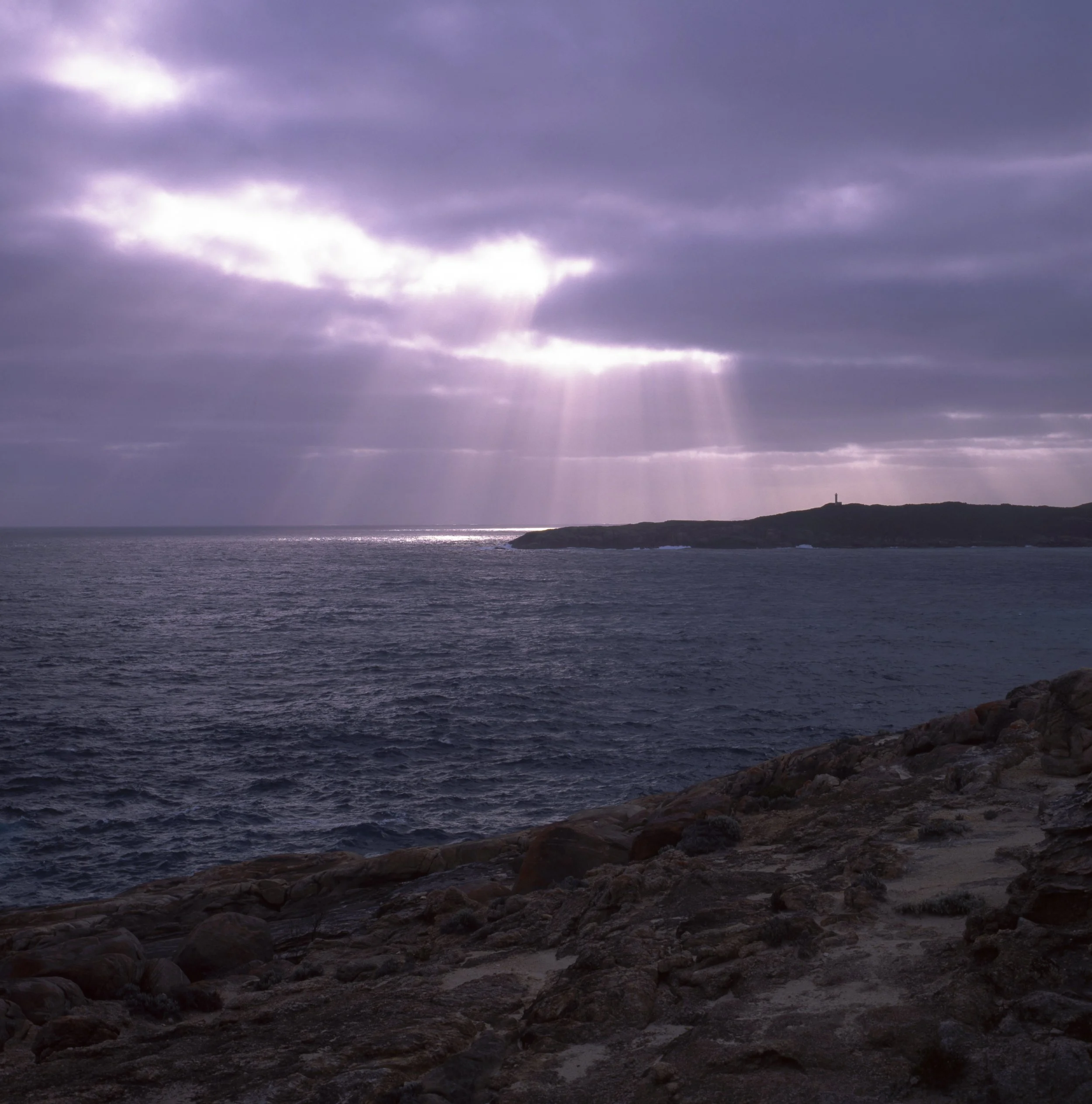 Dramatic storm clouds with rays of light breaking through over the ocean coastline, Australia — 120 film photograph