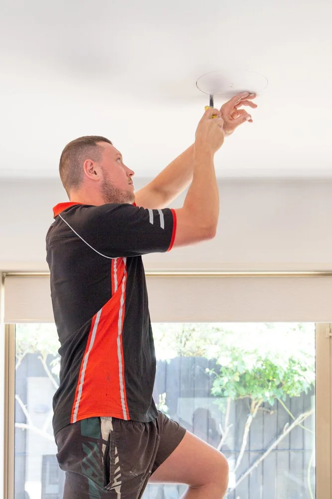 modserve technician installing home ventilation by cutting round hole in ceiling for duct