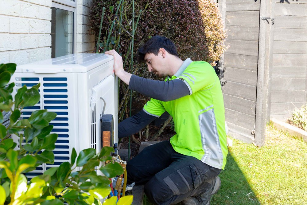 heat pump technician working on outdoor unit