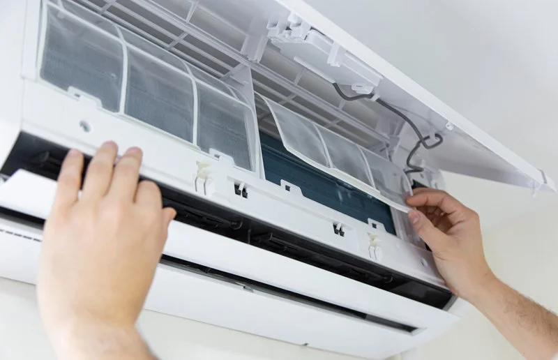 close up of hands installing cleaned filter into heat pump when servicing