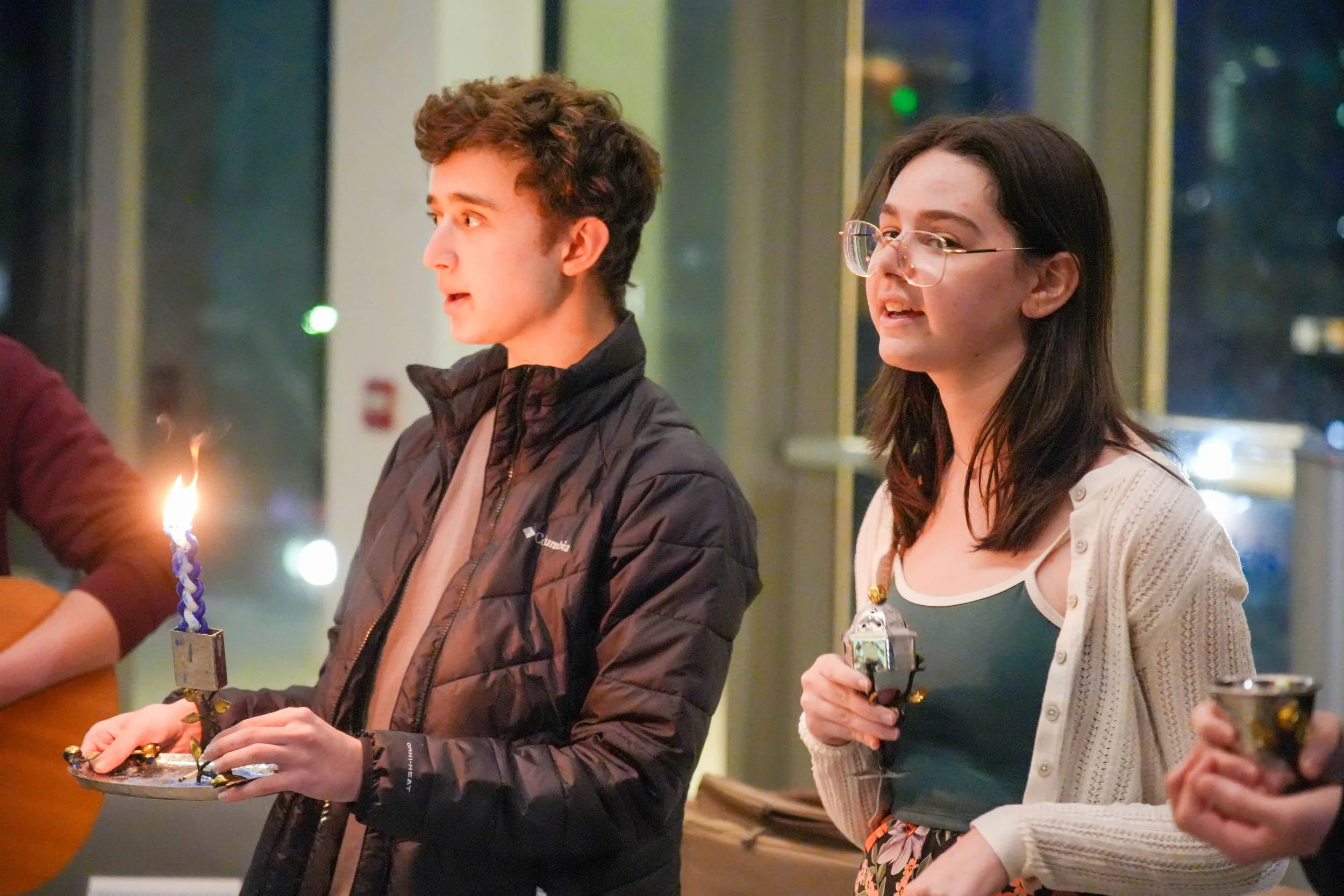 Students singing at havdallah, holding candles and spices