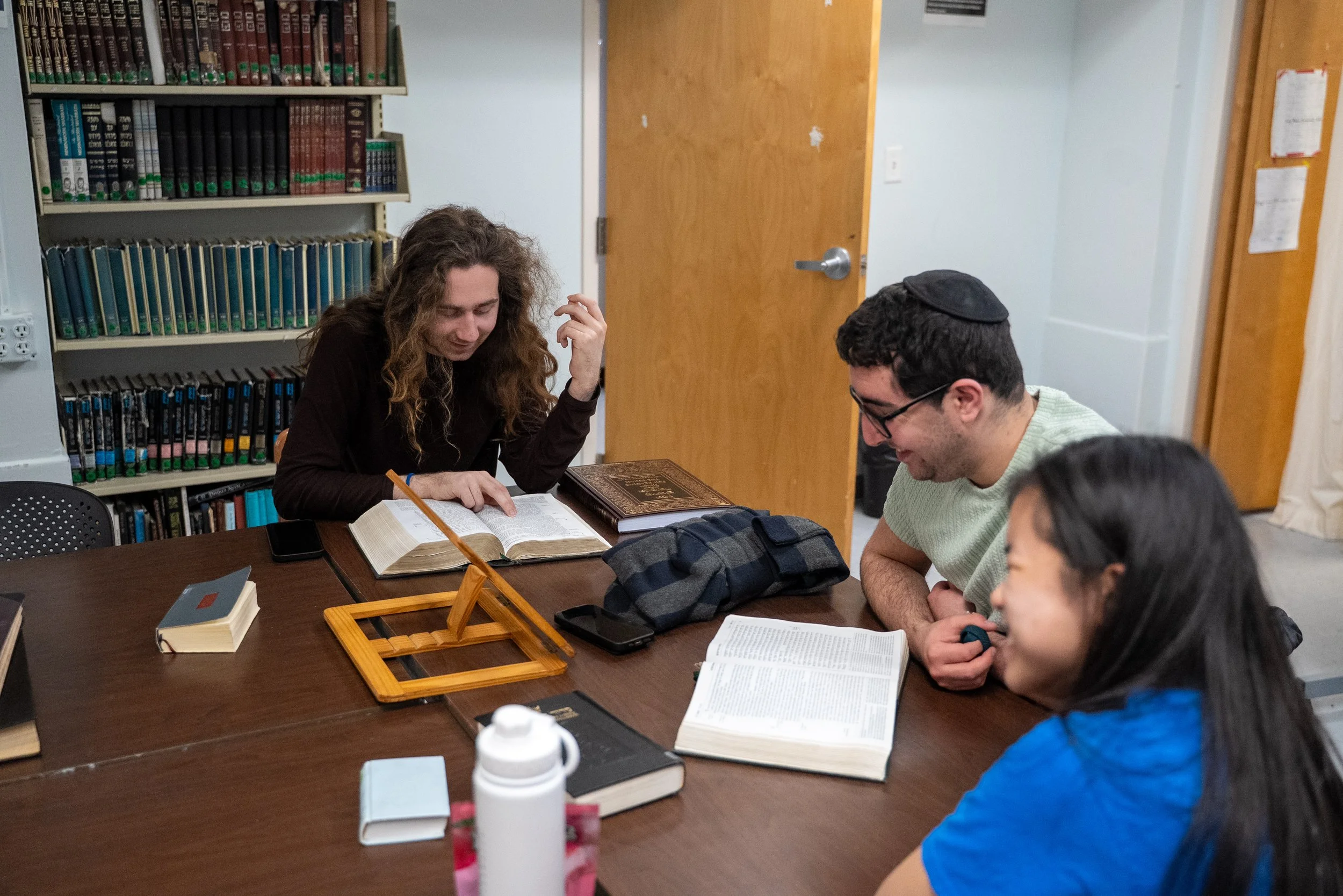 Students around a table reading a book in the Beit Midrash