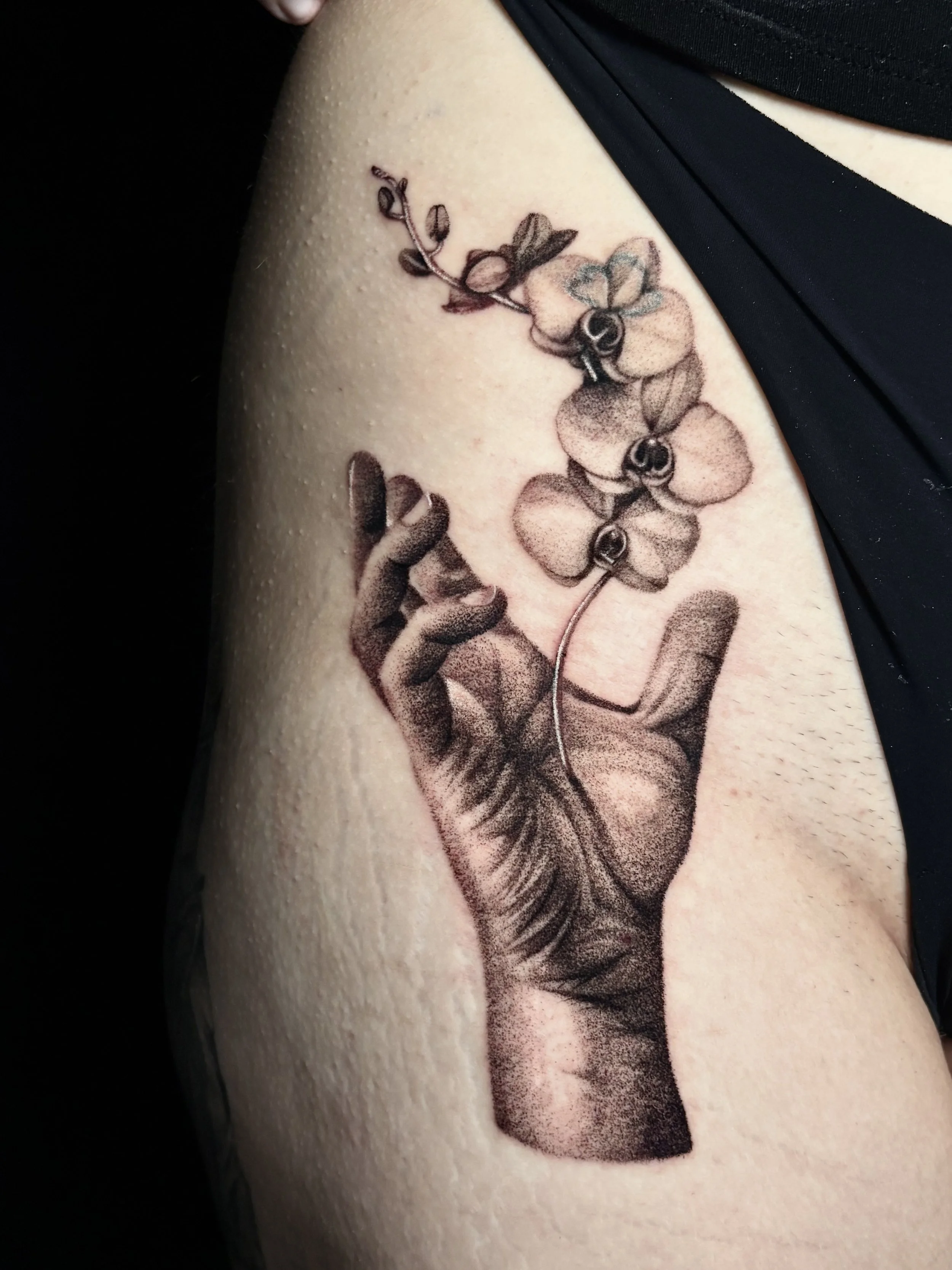 Tattoo of a hand holding a branch with three orchids on the arm. Surrealism Tattoo Done by Pablo at Ink Terminal Ottawa Gatineau