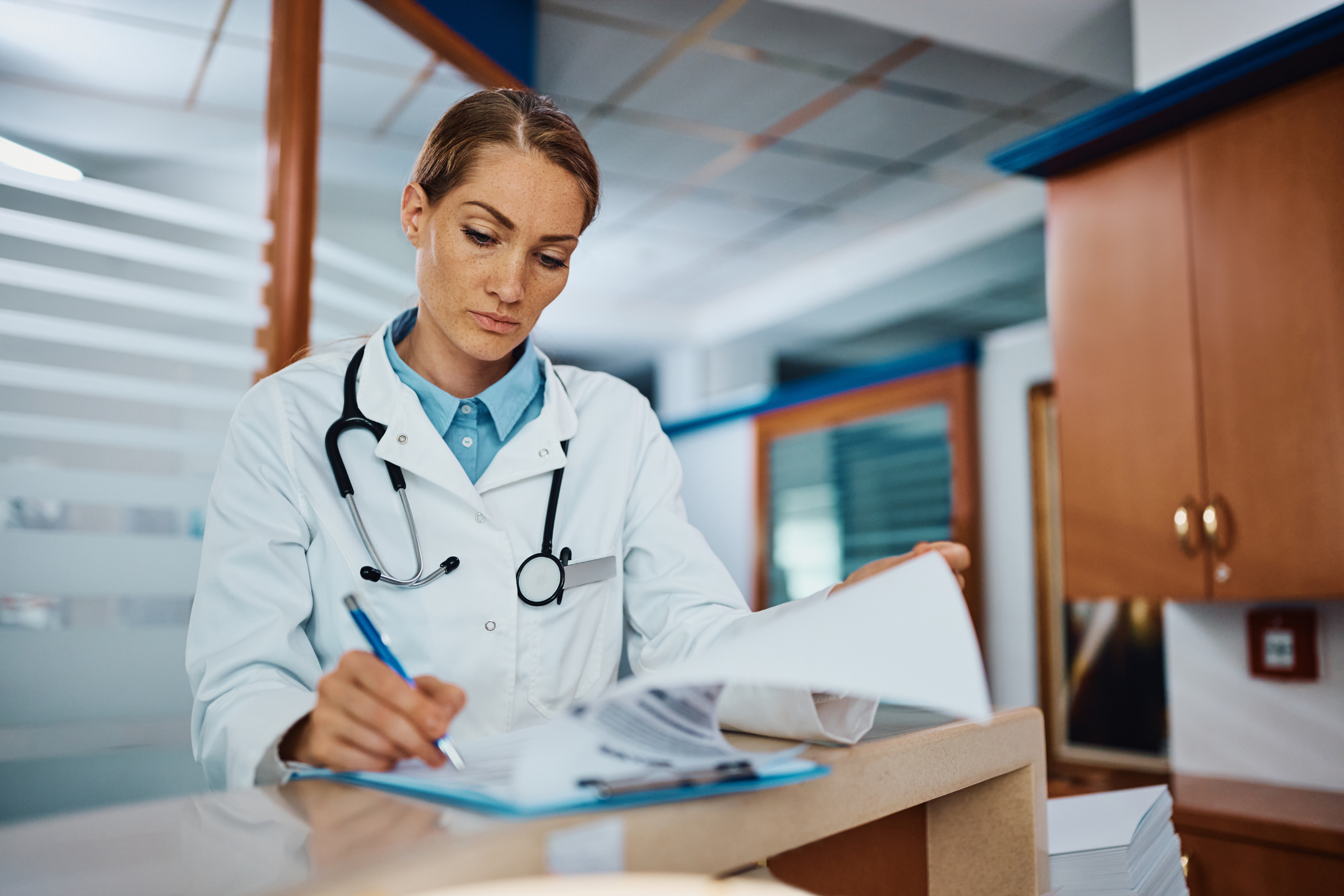 A doctor completes medical paperwork in a clinic.