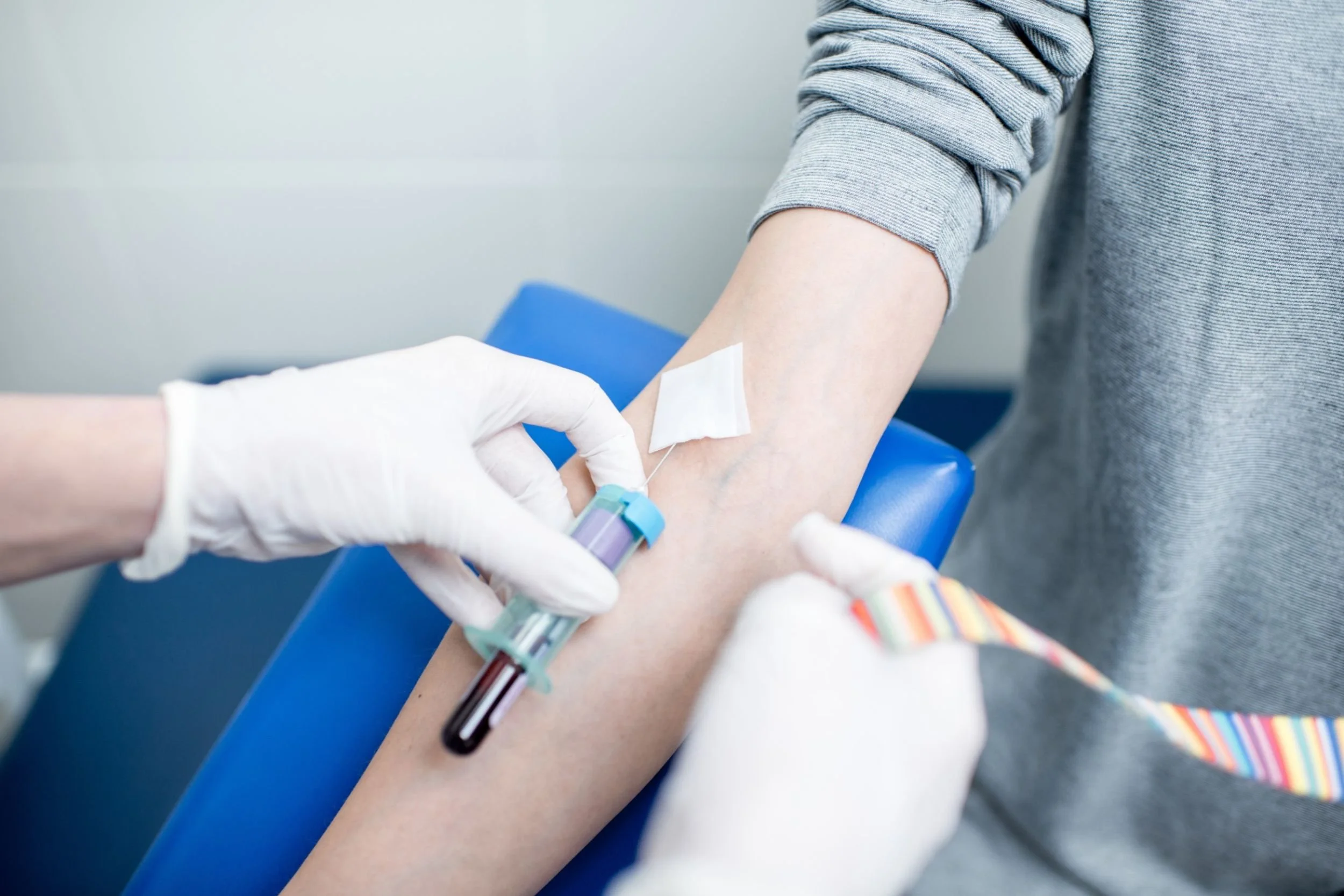 A close-up of a doctor collecting a blood sample from a patient in a clinical setting.