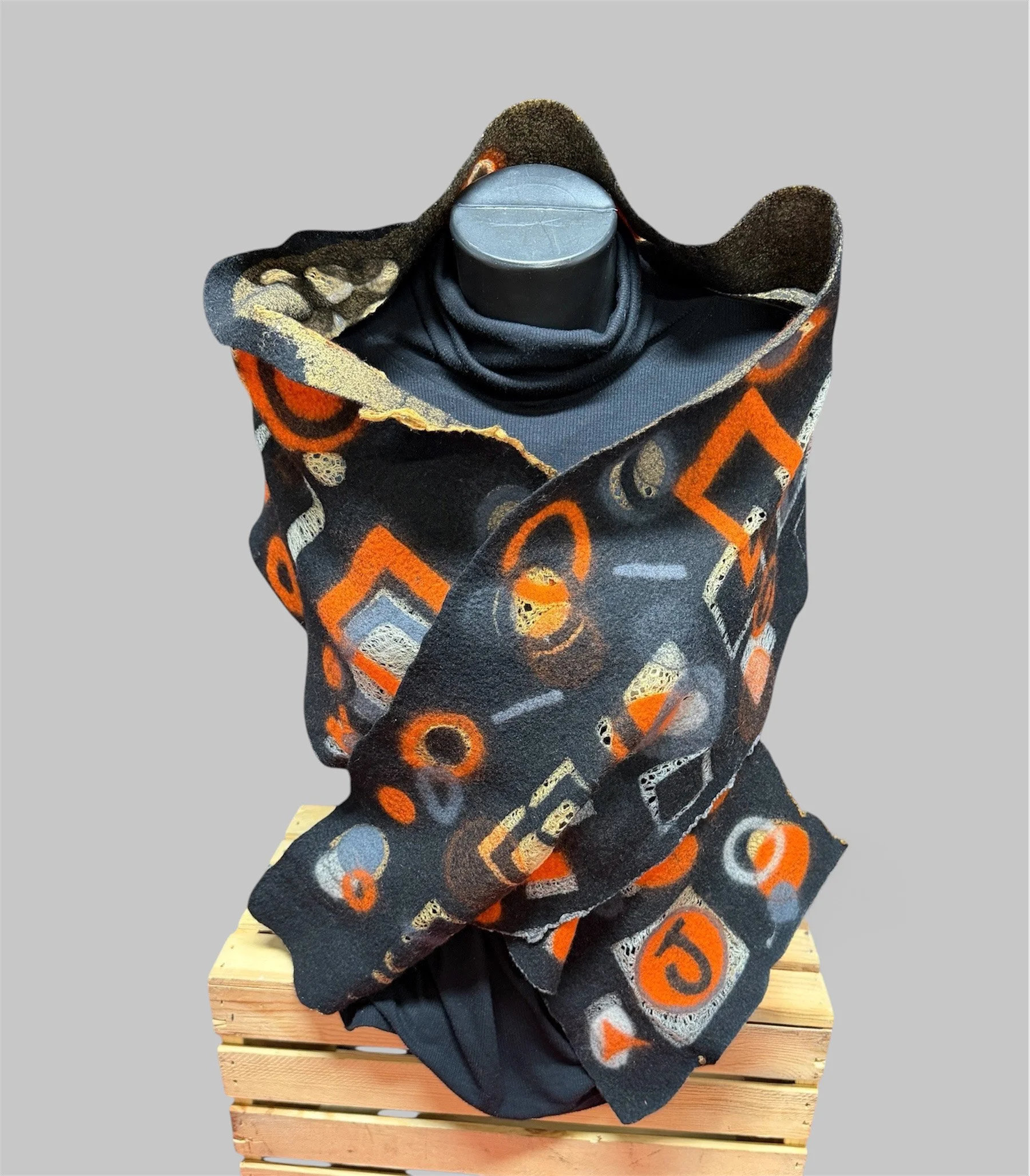 This dramatic merino wool/silk Nuno felt wrap features a rich black base accented with bold orange, gray, and cream abstract shapes.
 
67-1/2"L x 10-12-1/2"W