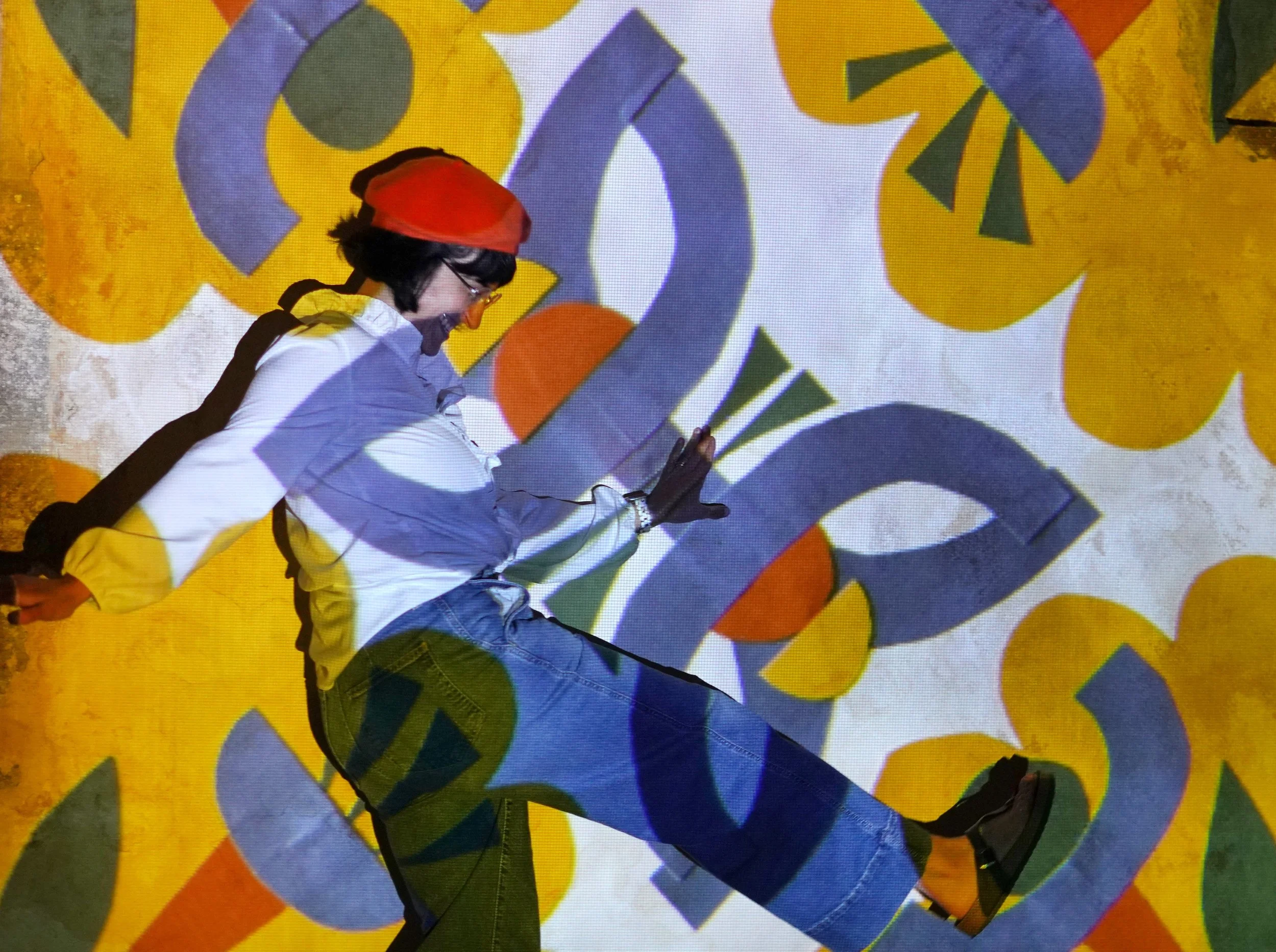 owner Bethany dancing in front of a block print mural