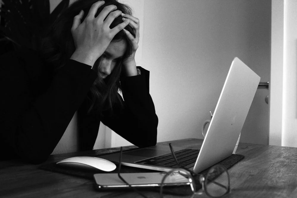 Frustrated Business owner looking at their bad branding and website on a laptop.