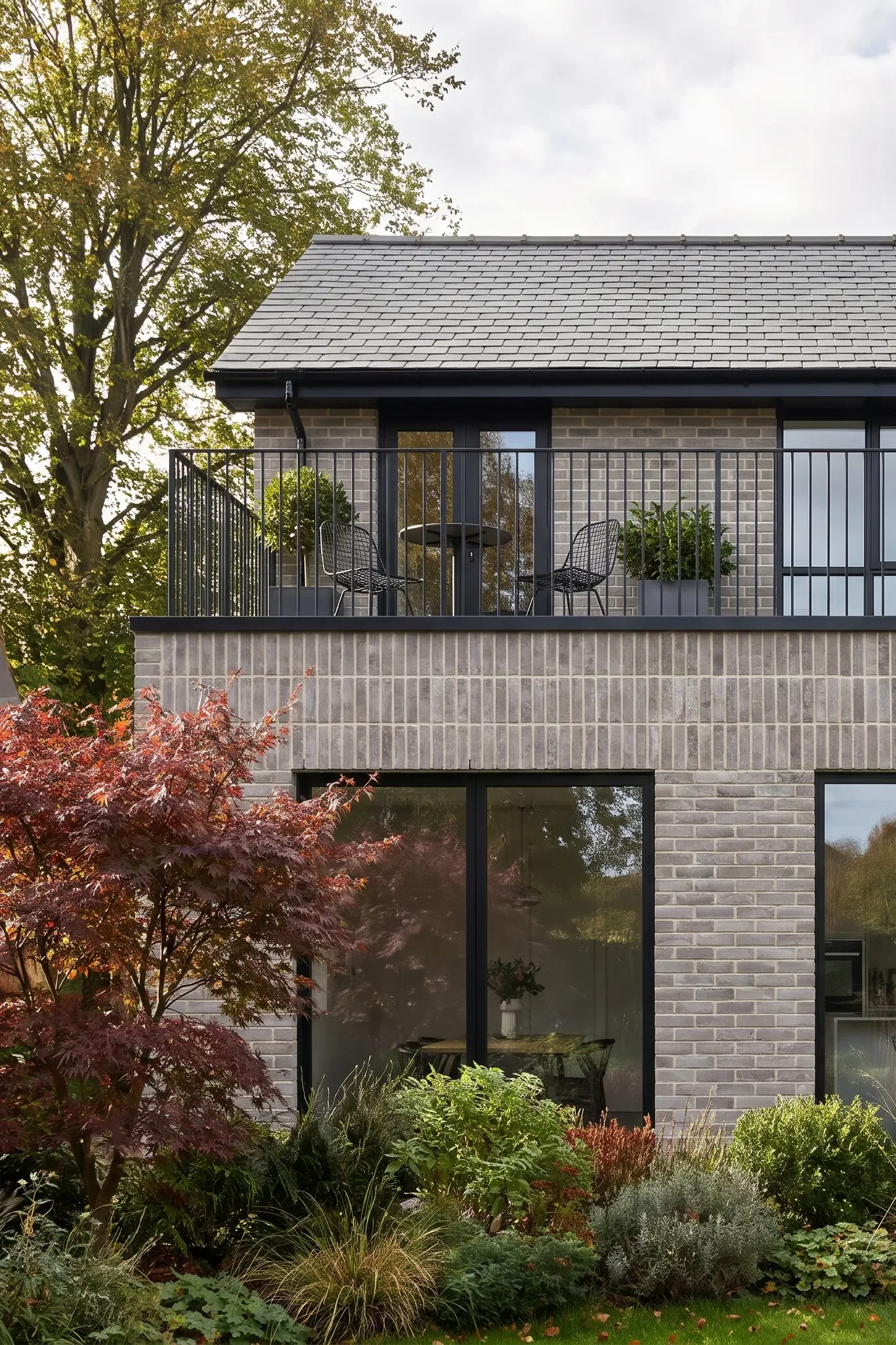 A first-floor balcony overlooks the garden beneath a slate roof