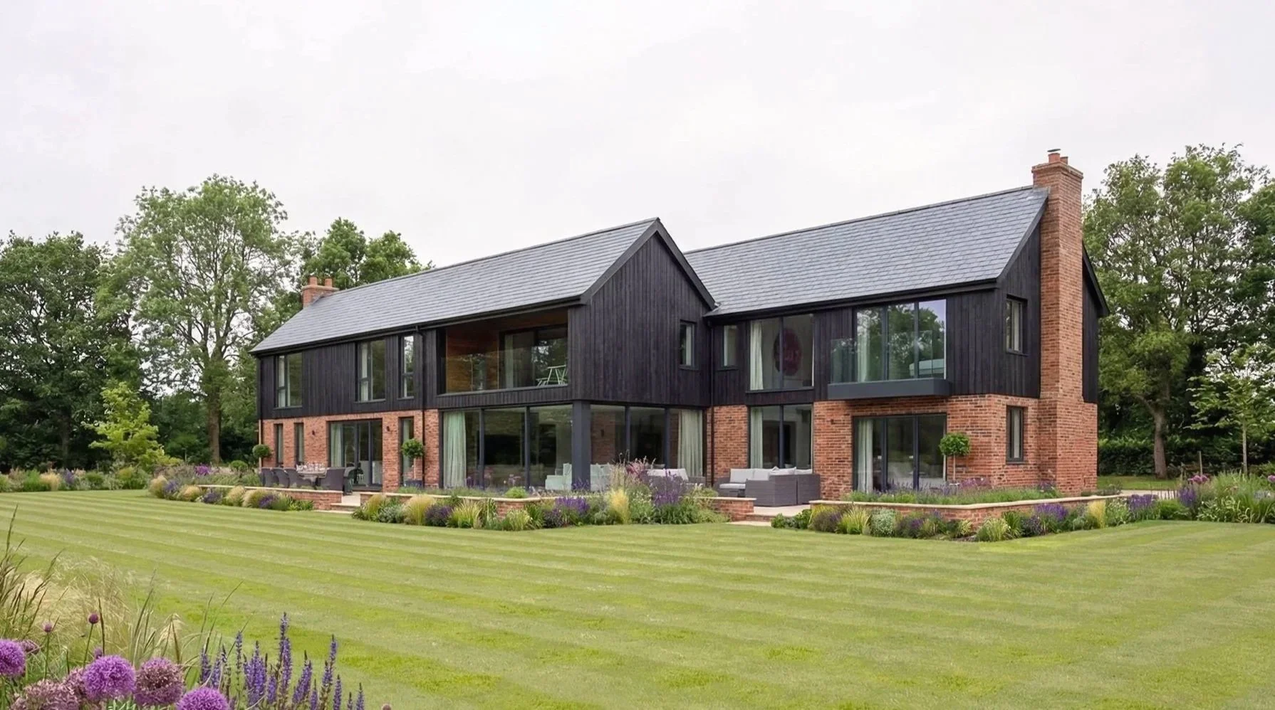 Carlton Lodge, near Worksop, is a major renovation and extension: a two-story house with black wooden siding and red brick accents, surrounded by woodland and fields