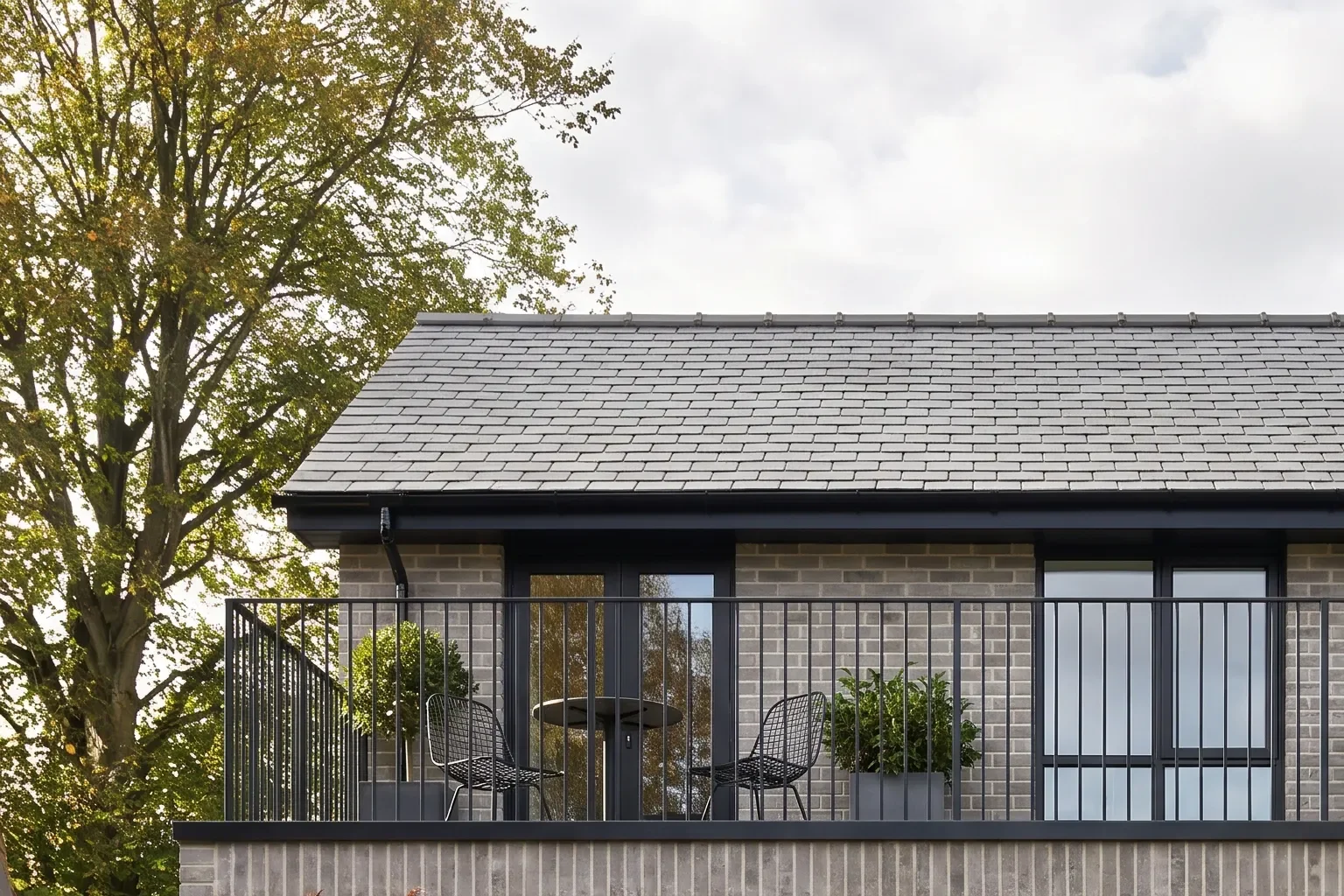 Slender black balustrades and planted pots define the balcony