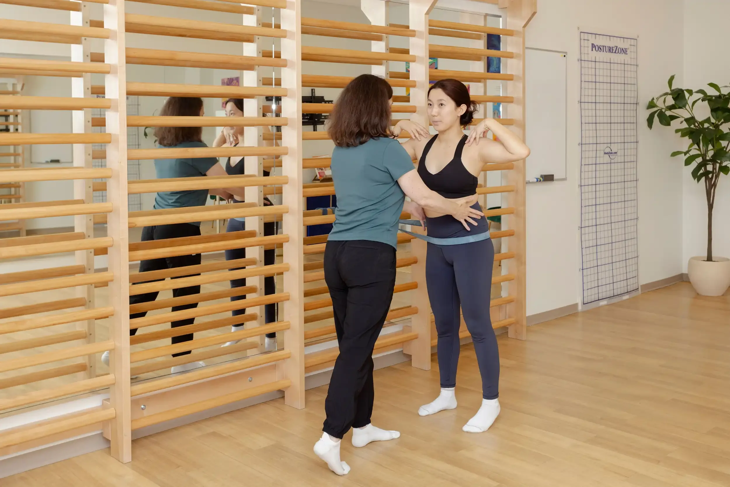 physical therapist guiding an adult patient in a standing Schroth exercise