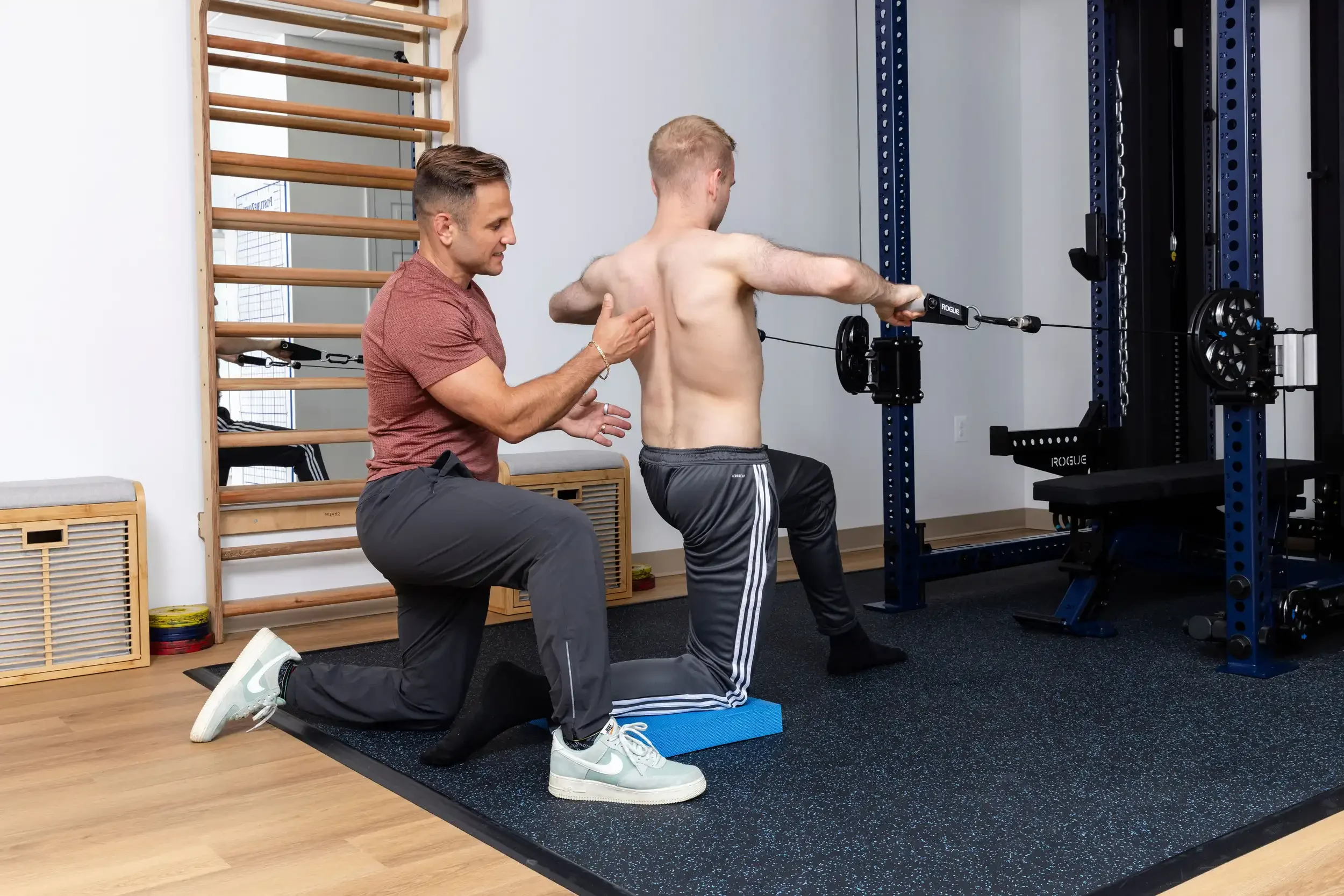 physical therapist guiding adult patient with weightlifting exercise