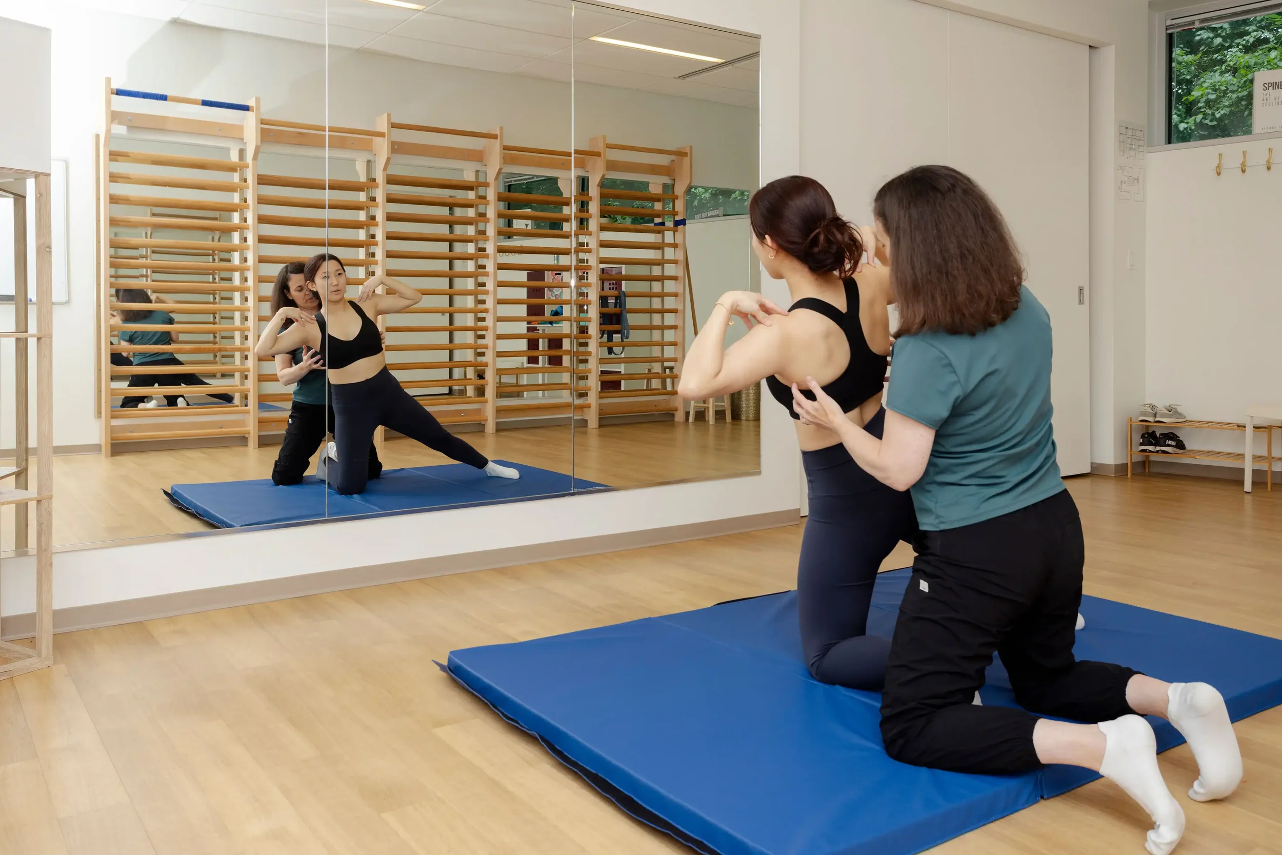 physical therapist guiding an adult patient in a kneeling Schroth exercise